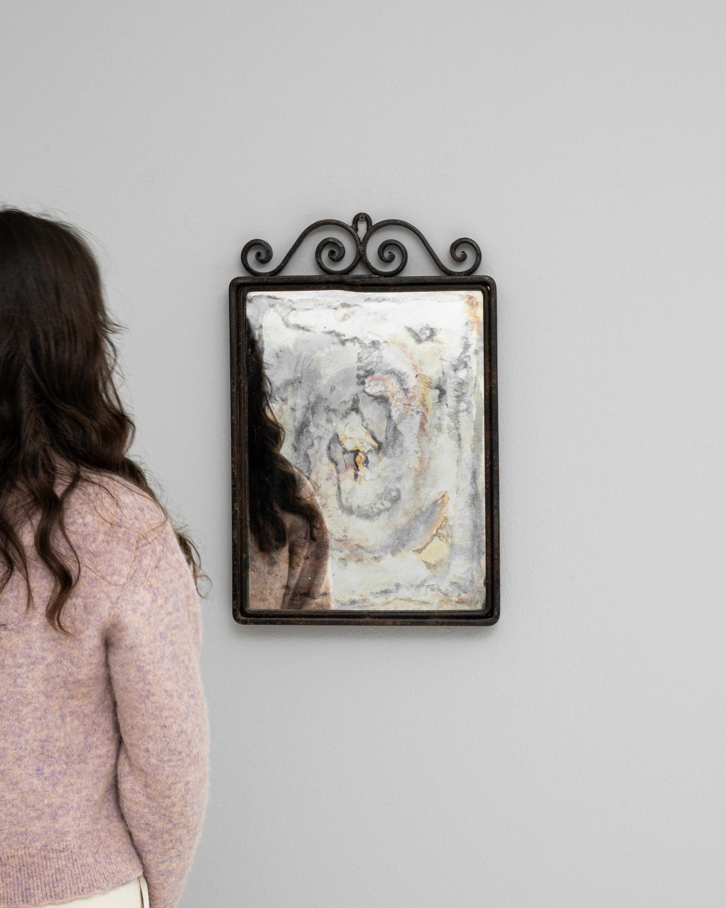 This 20th Century French Metal Mirror exudes an air of industrial chic with its minimalistic yet striking design. The simple, squared frame is crafted from metal, featuring a rich patina that tells the story of its journey through time. Adding a