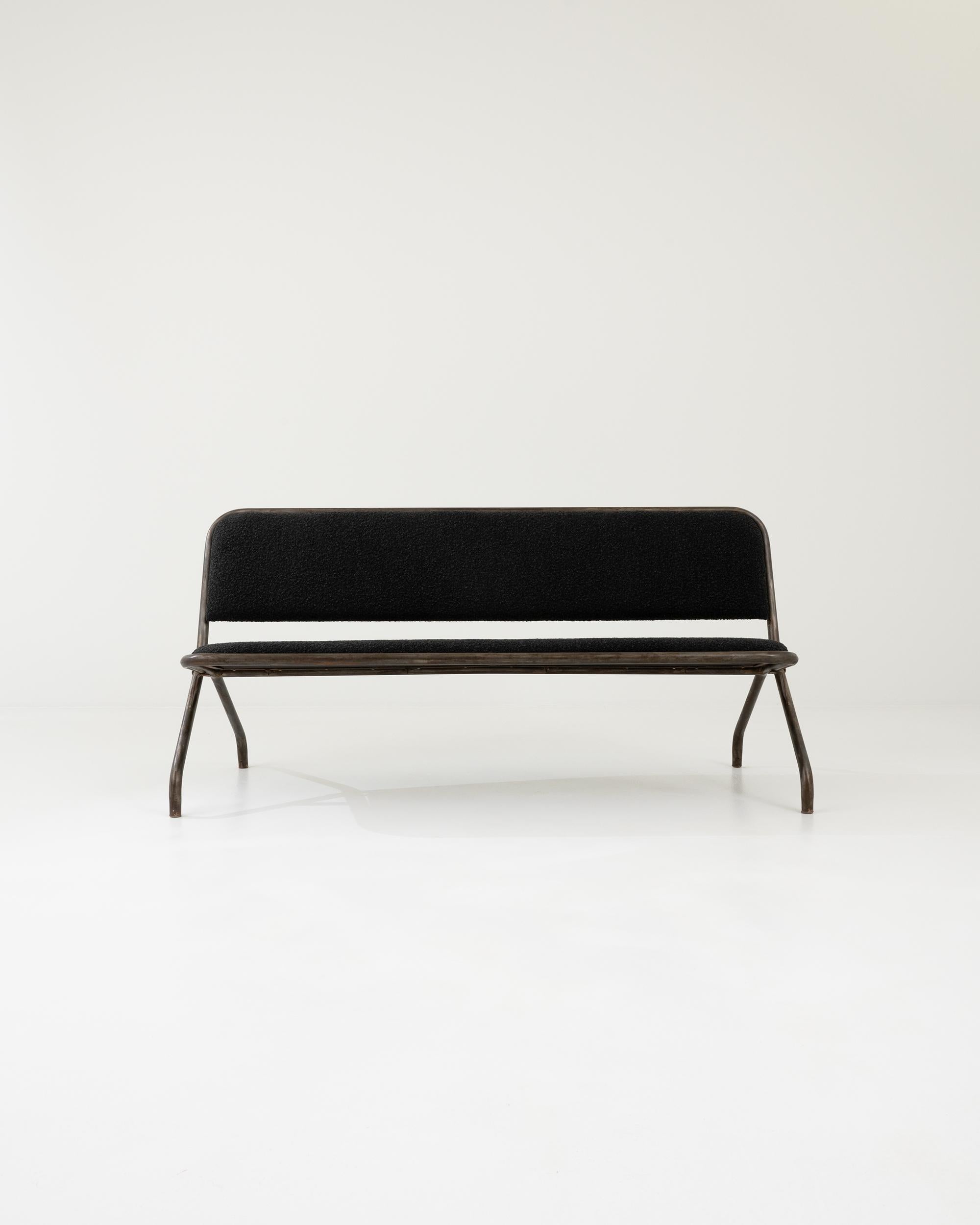 A metal upholstered bench created in 20th century France. Industrial yet approachable, this straightforward folding bench exudes a surprising coziness. With a minimal design, this bench allows its industrial material to shine, with a time-earned