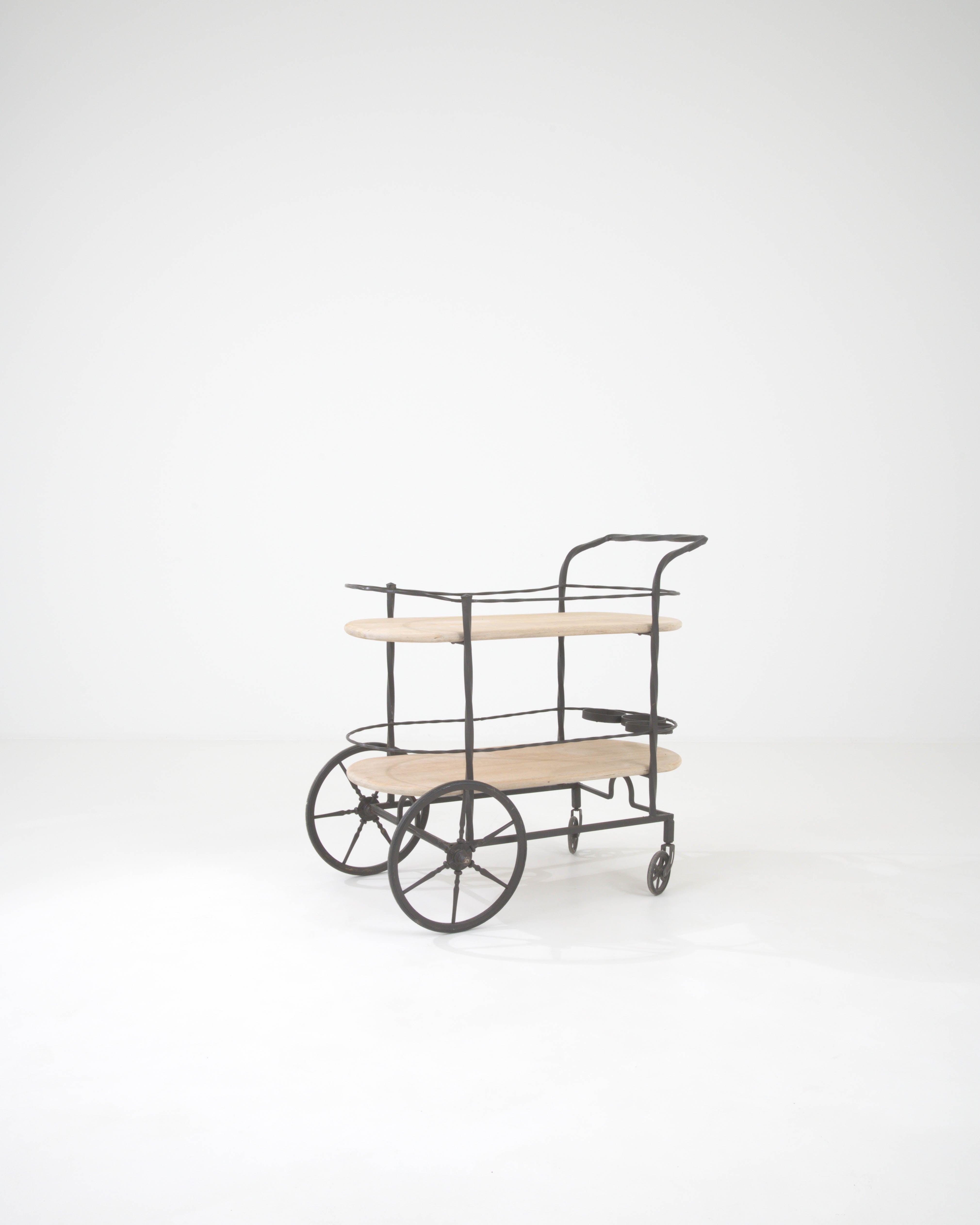 Elevate your entertaining with this exquisite 20th Century French Metal & Wooden Bar Cart on Wheels. This stylish bar cart features a sturdy metal frame complemented by beautifully crafted wooden shelves, offering a perfect blend of industrial and