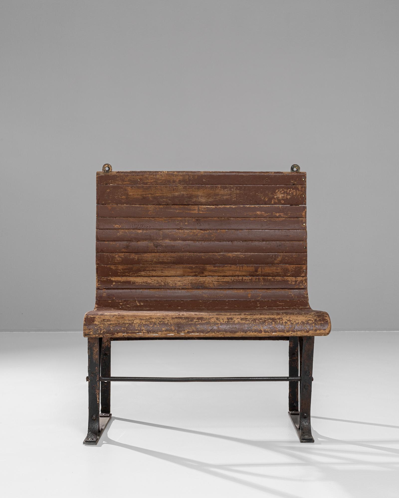 This 20th Century French bench seamlessly combines rustic charm with industrial functionality. The seat and backrest, crafted from aged wooden slats, showcase a rich patina, revealing decades of character and history. The robust metal frame provides