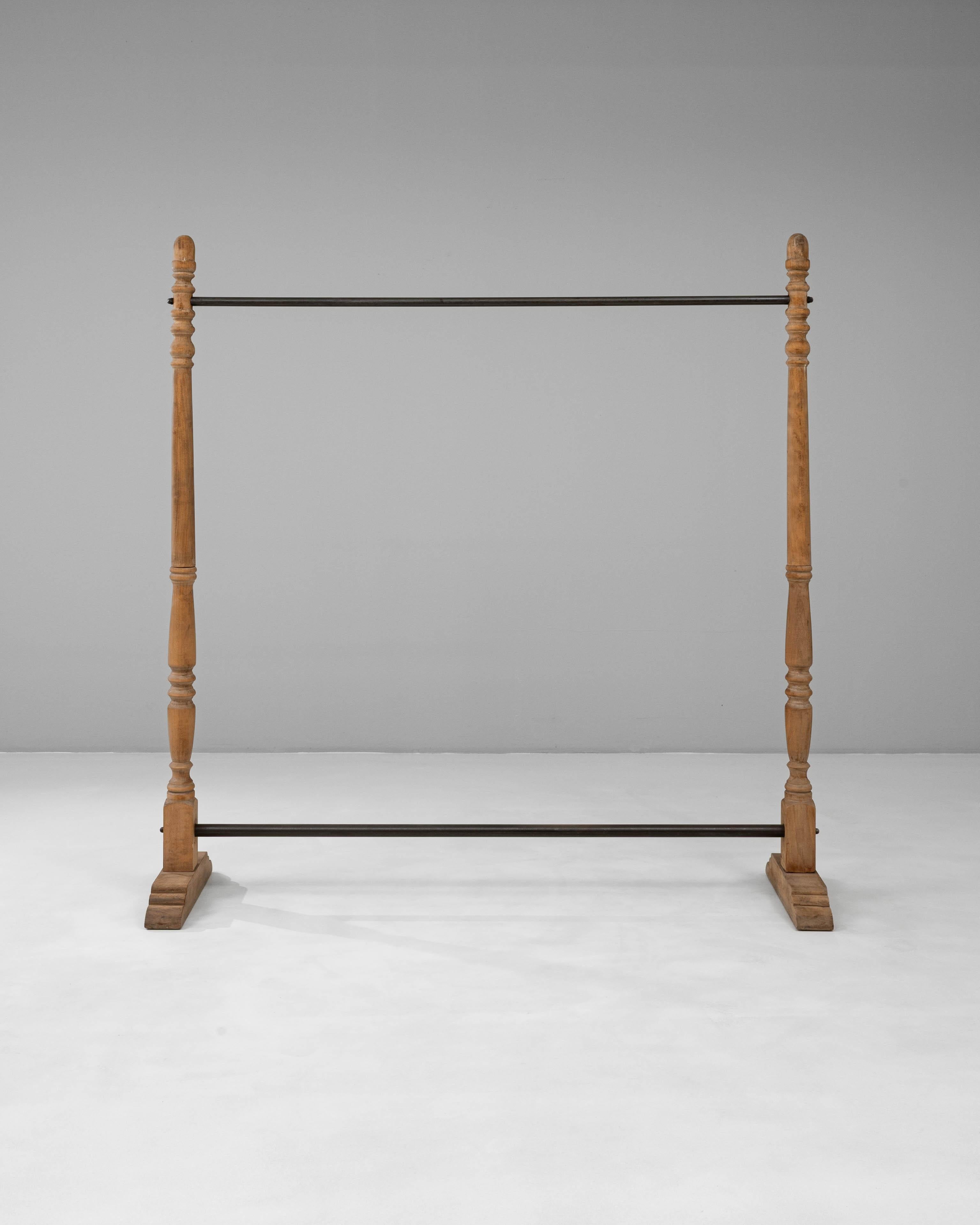 Questo appendiabiti francese del XX secolo combina il fascino rustico con un design pratico, realizzato con montanti in legno torniti e robuste aste in metallo. I montanti in legno presentano dettagli tradizionali con una patina naturale che