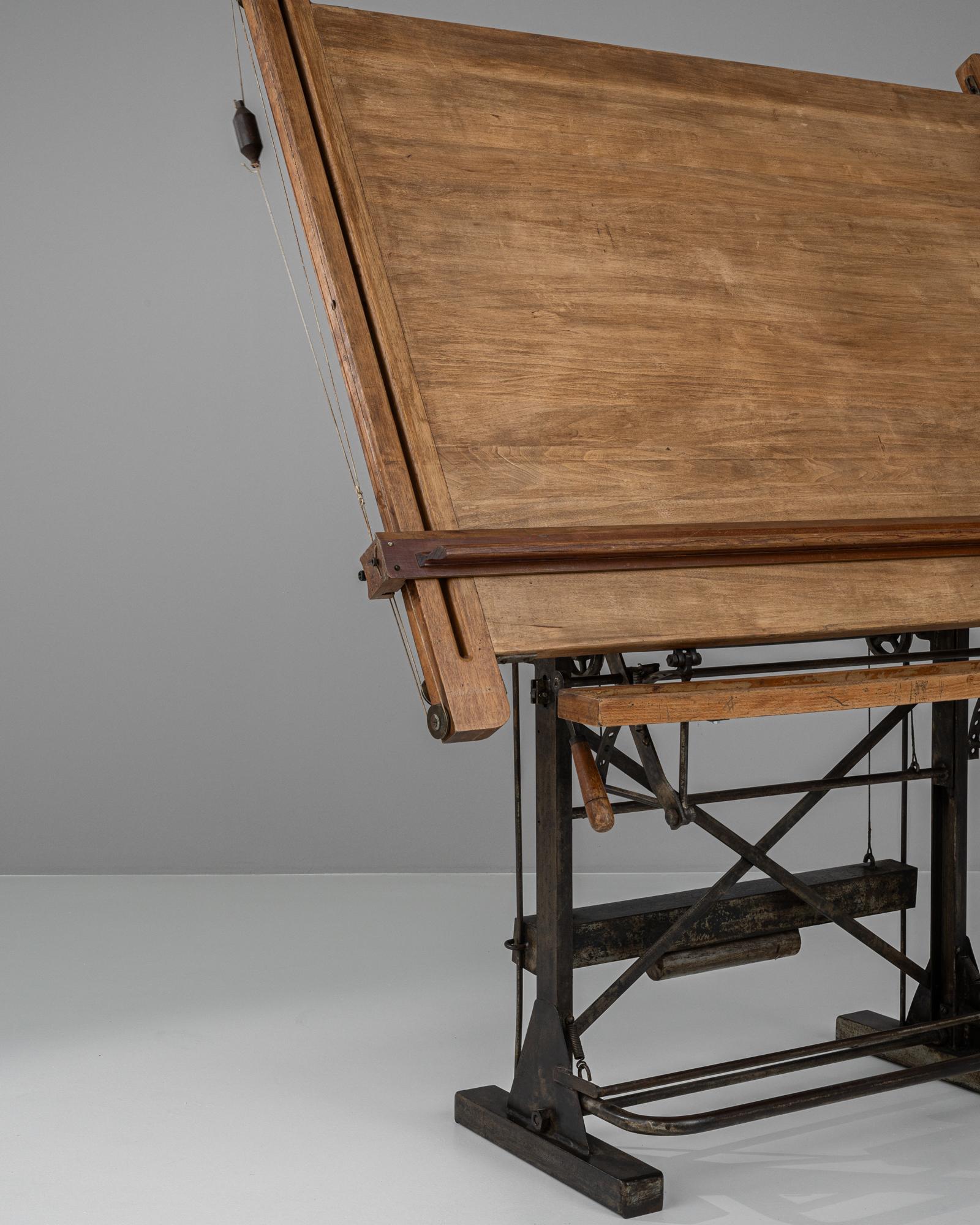 Cette table à dessin française du XXe siècle allie fonctionnalité et charme industriel. Fabriquée en bois et en métal, cette pièce est dotée d'un mécanisme de basculement soutenu par un cadre en fer robuste. Le plateau en bois naturel, riche en