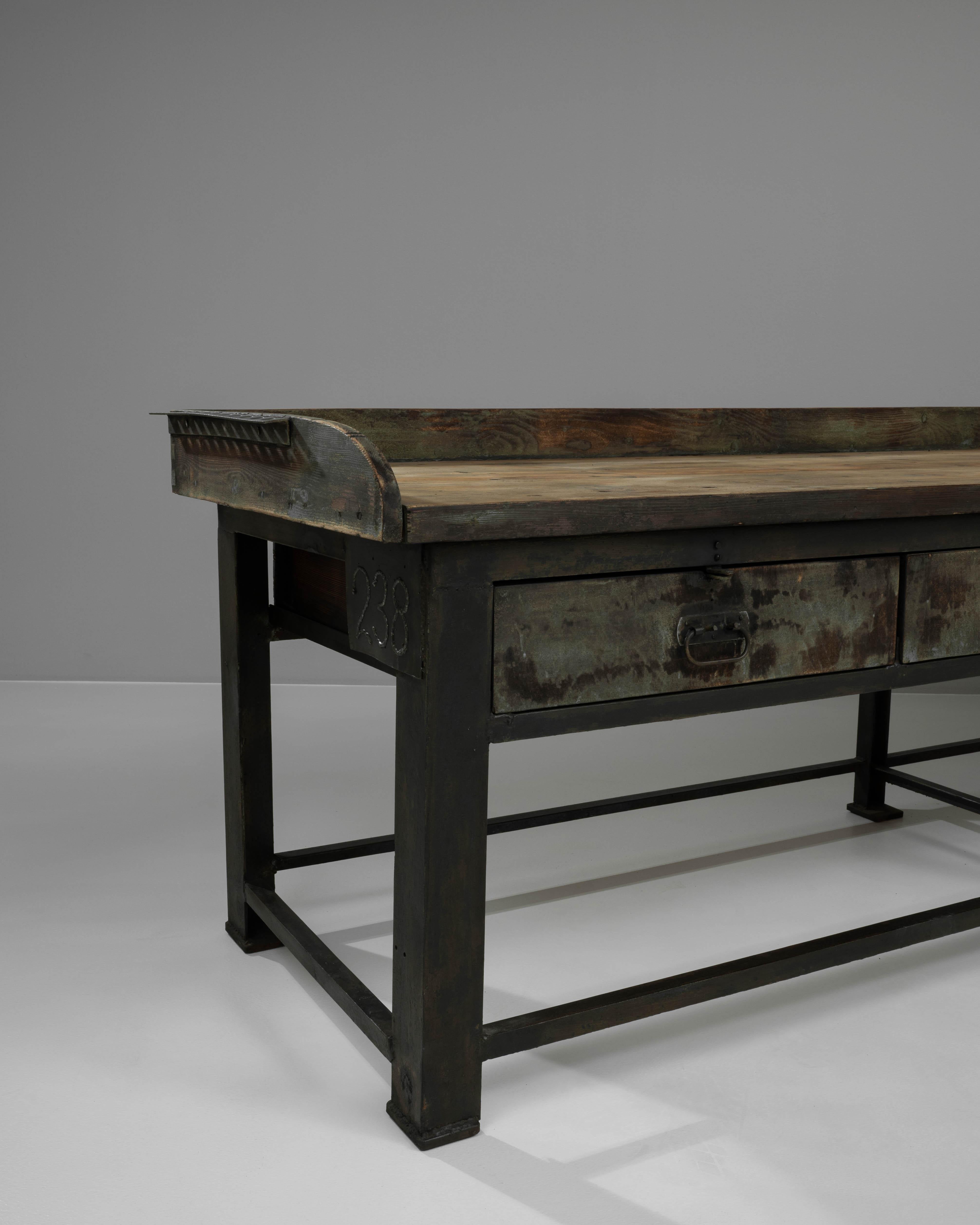 Questo robusto tavolo da lavoro francese del XX secolo combina magnificamente il fascino industriale con la praticità rustica. Il piano del tavolo, realizzato in legno invecchiato, mostra una ricca patina che porta i segni del tempo e dell'uso che