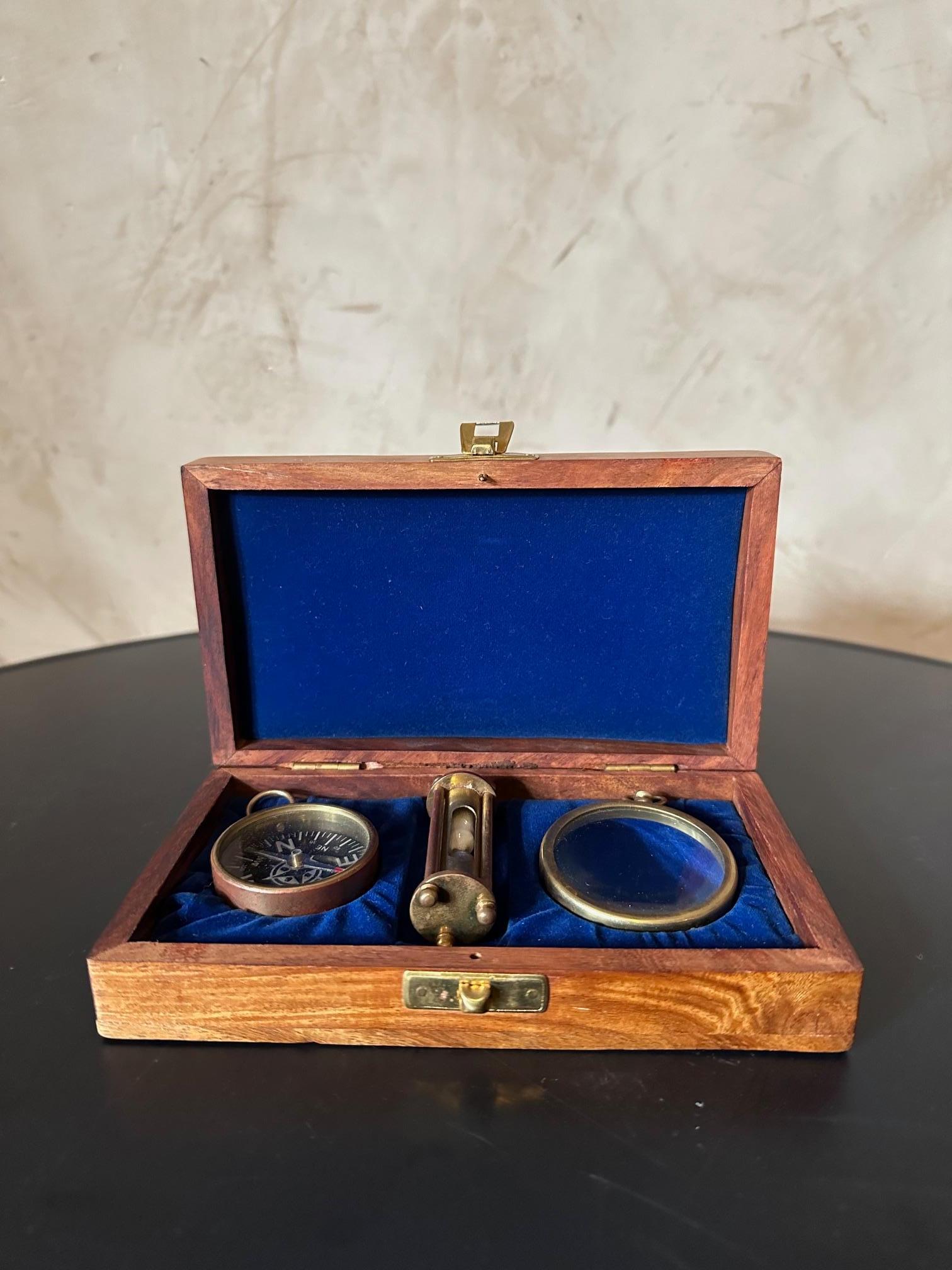 Small nautical wooden box dating from the 1950s composed of several brass objects, a compass, an hourglass and a magnifying glass. A boat anchor depicted on cover. Good quality and good condition.