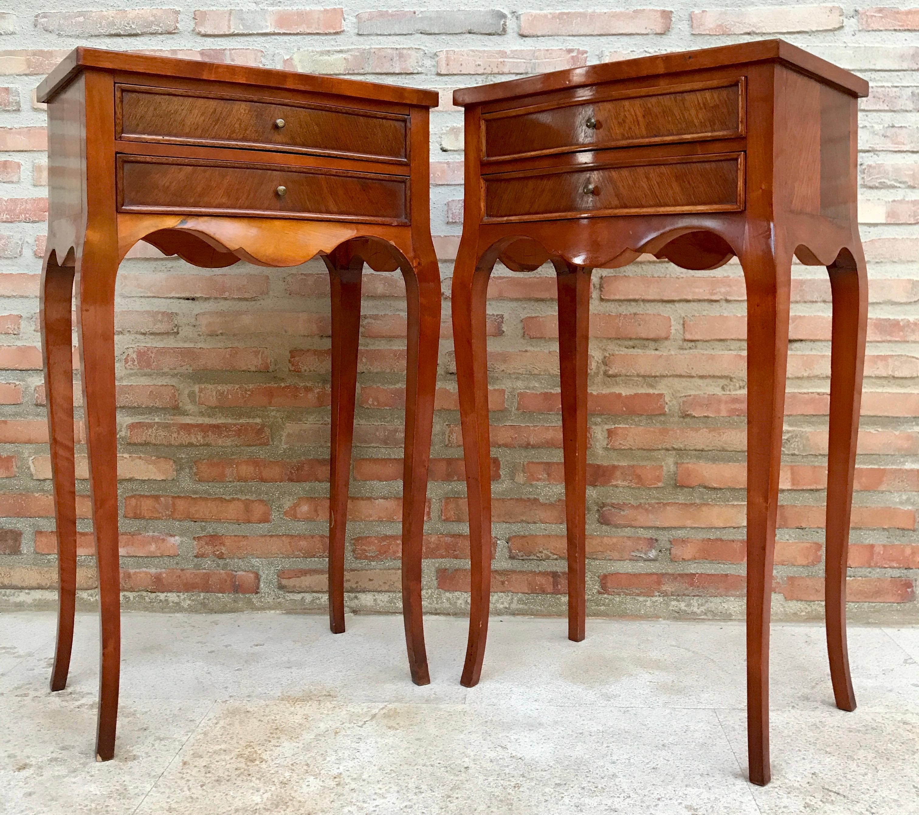20th century pair of French nightstands with two-drawers and cabriole legs. The tables have a beautiful carved in legs and apron front. 
Really nice patina.