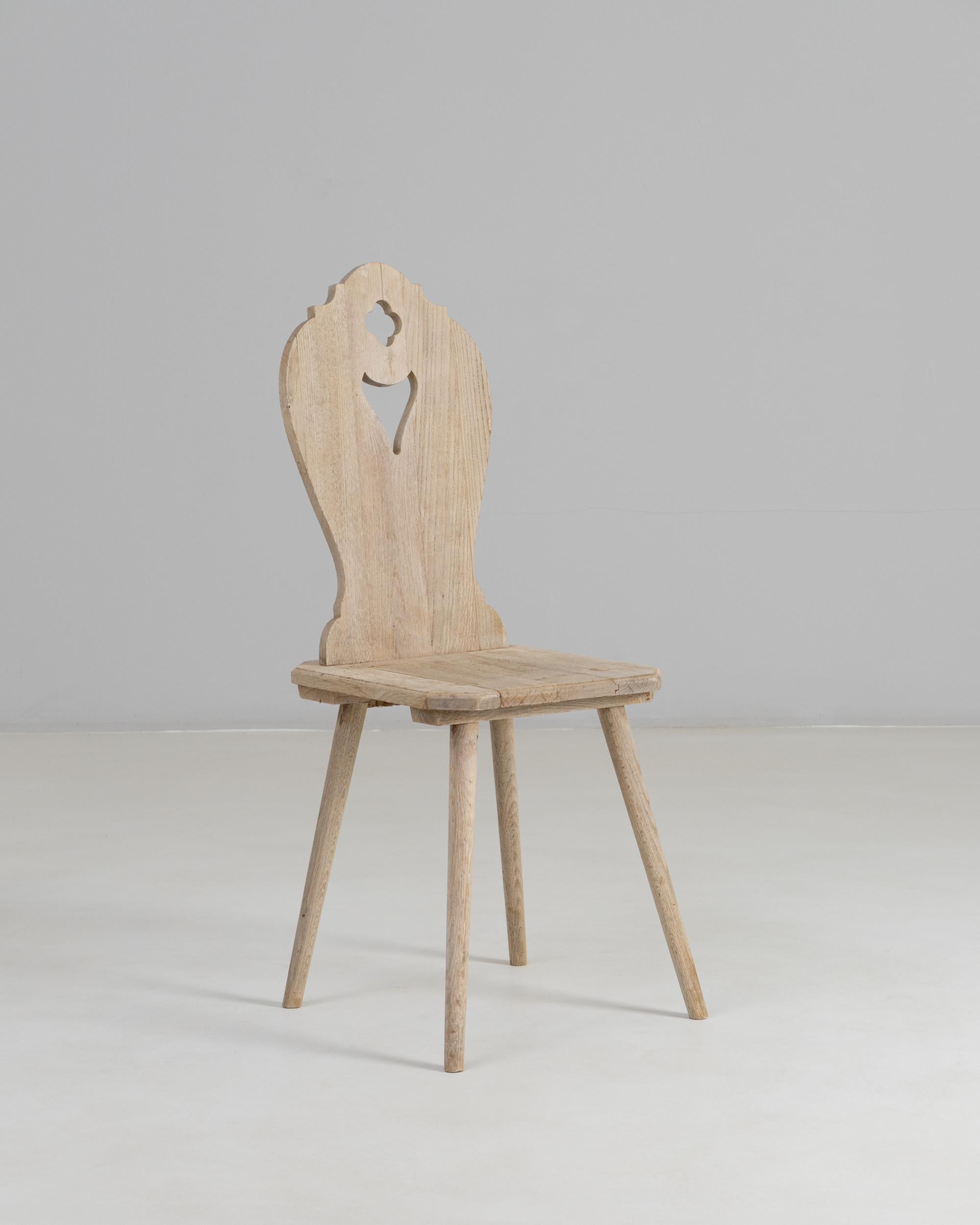 20th Century French Oak Alpine Dining Chair. This charming dining chair captures the rustic, handcrafted spirit of traditional Alpine design. Made from solid oak, it features a sculpted backrest with a distinctive cut-out motif, lending both