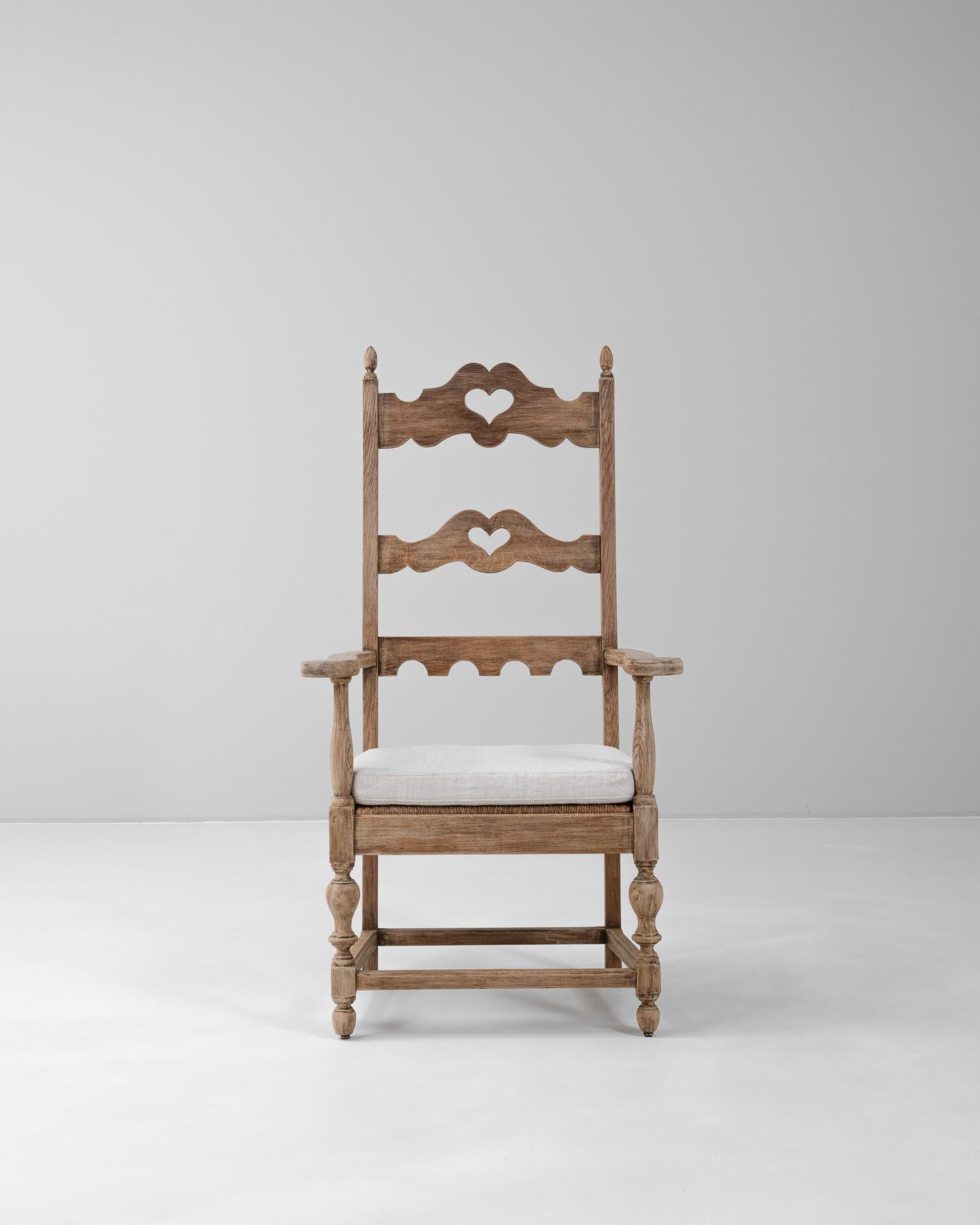 Este sillón francés de roble del siglo XX desprende encanto rústico con sus caprichosos recortes de corazón y detalles tallados a mano. Fabricada en roble macizo, la silla tiene un respaldo alto en forma de escalera con dos listones perfilados, cada