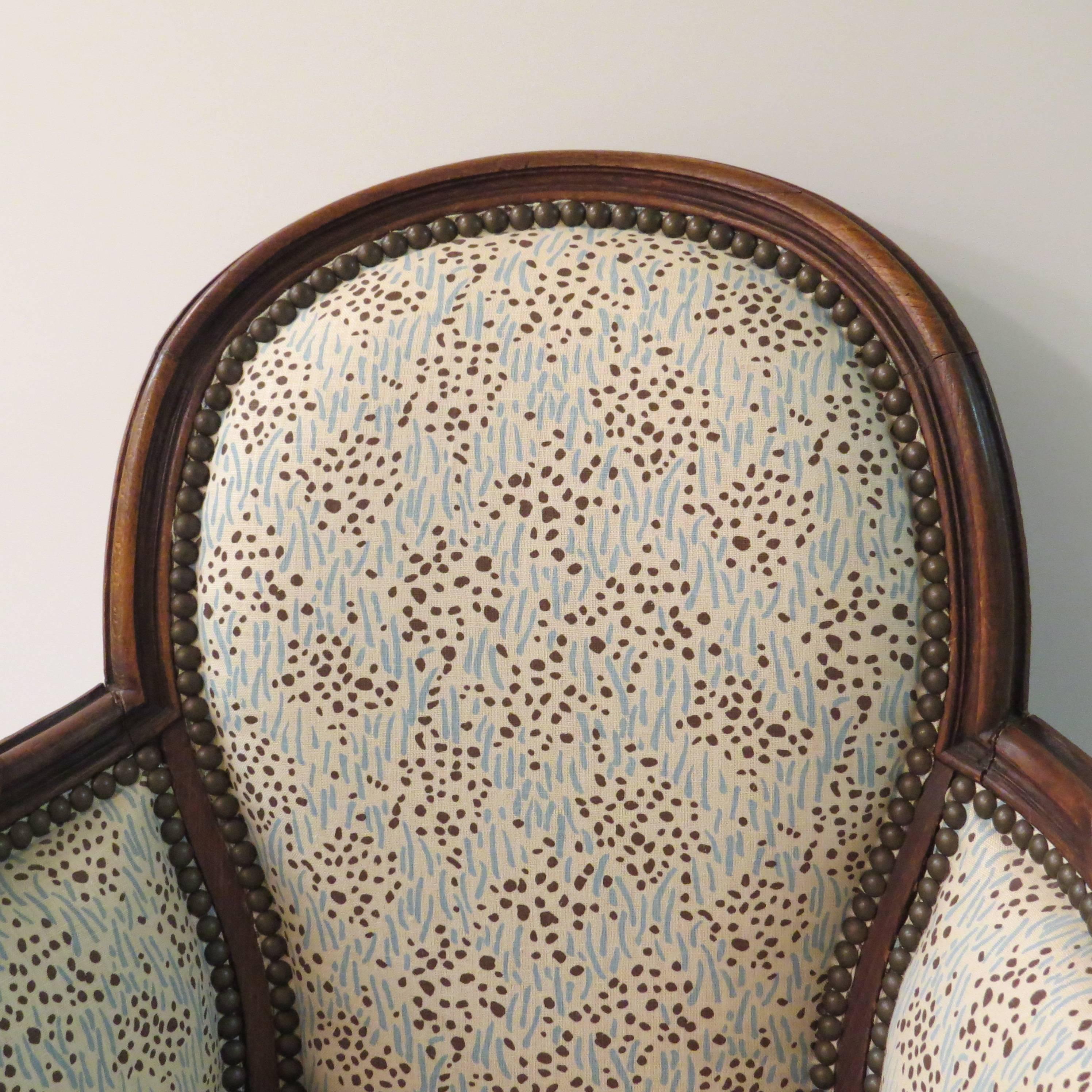 Petite bergere made from oak. New upholstery in patterned cotton with nail head trim, 20th century model from France.