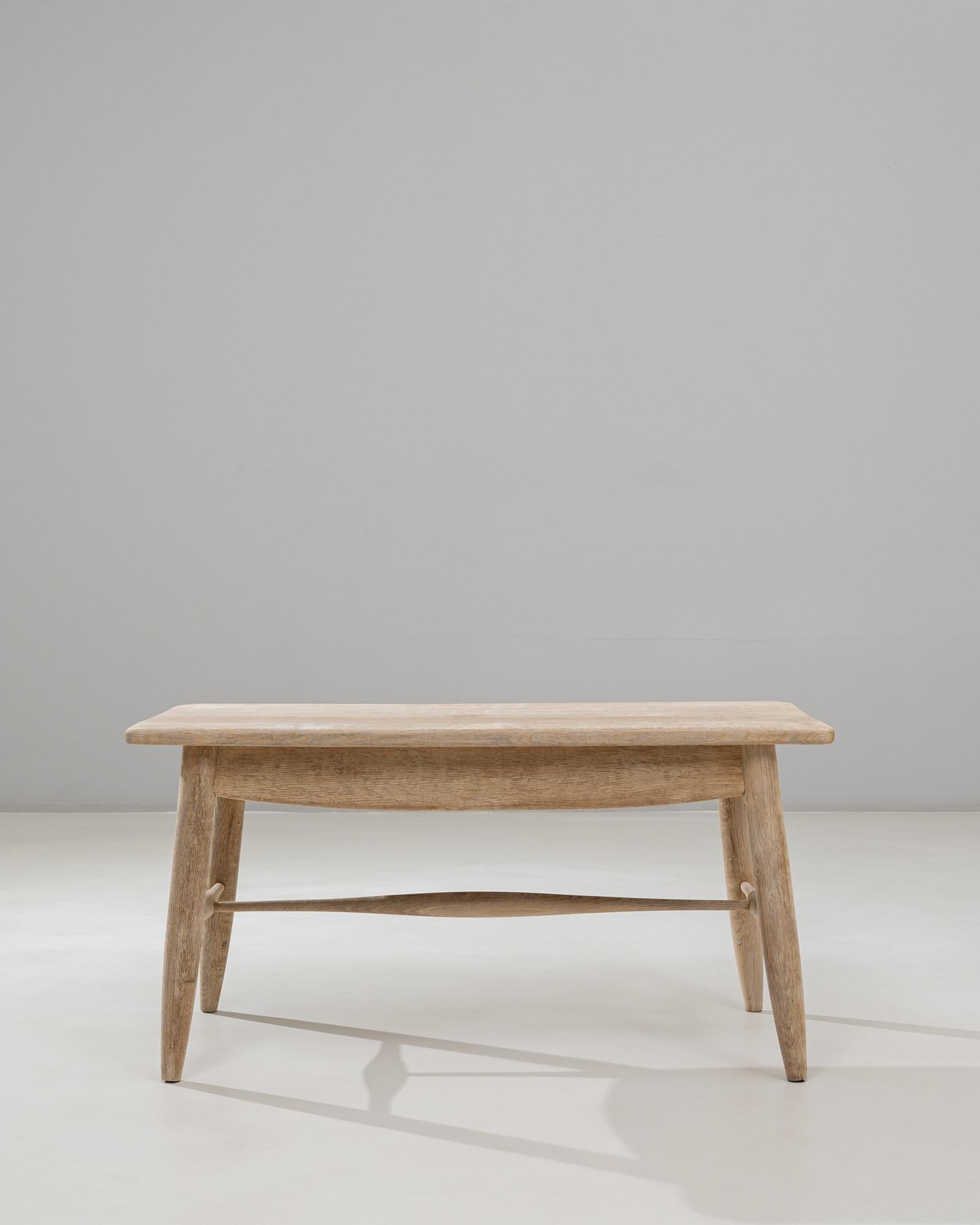 This 20th Century French oak coffee table embodies the understated beauty of provincial craftsmanship with its simple, well-balanced form and warm, natural patina. The rectangular top features softly rounded edges and a subtly textured surface that