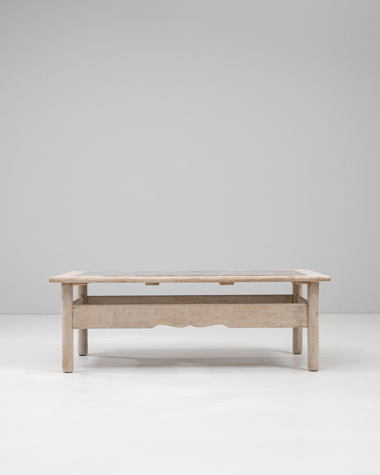 Crafted in France during the 20th century, this oak coffee table features a handsome rectangular silhouette topped with a richly veined marble surface. The bleached oak base offers a soft, natural tone with rounded legs and scalloped apron details,