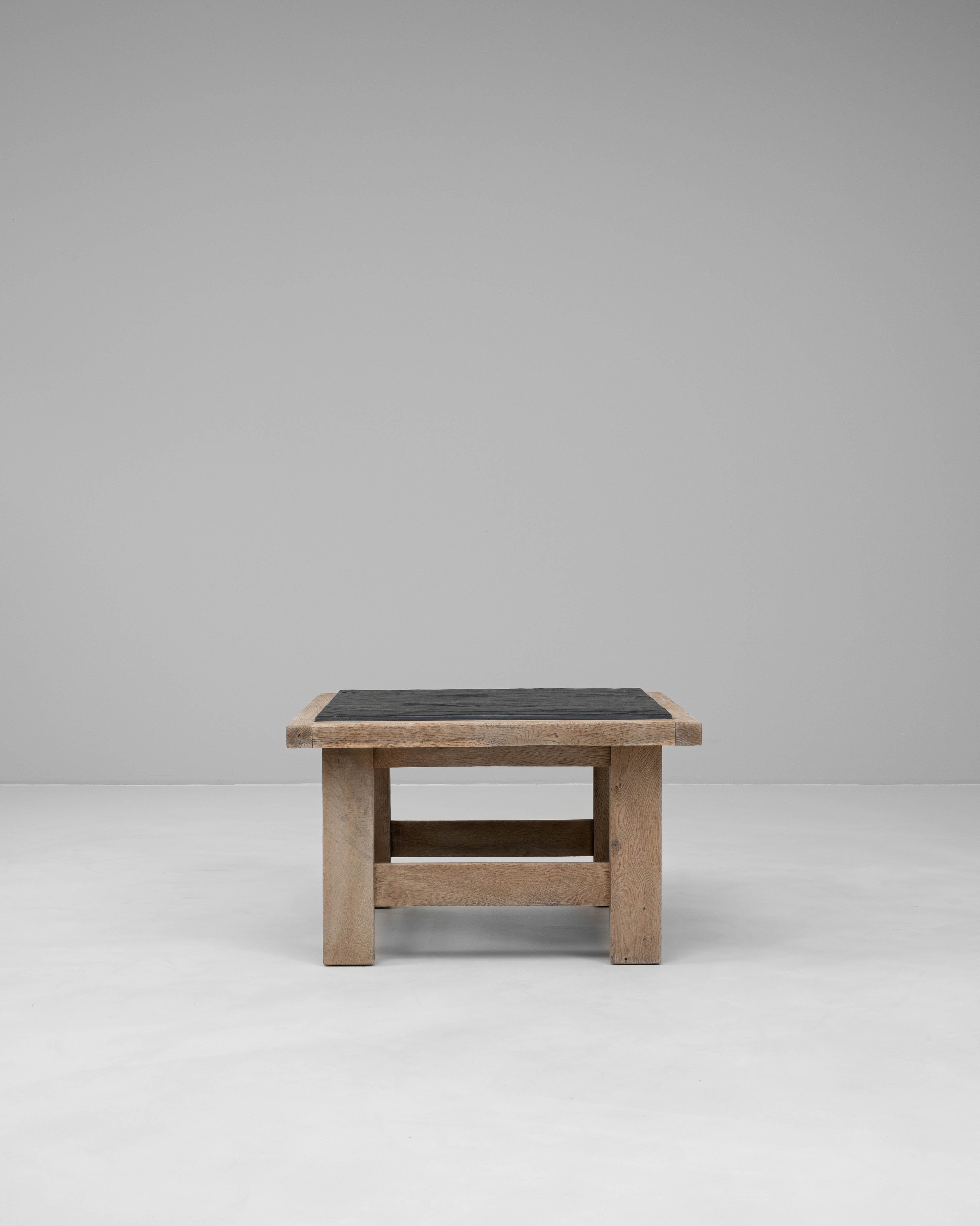 This 20th century French coffee table showcases a harmonious blend of natural materials and robust craftsmanship. The solid oak frame features clean, geometric lines and a lightly bleached finish that highlights the wood’s rich grain and texture.