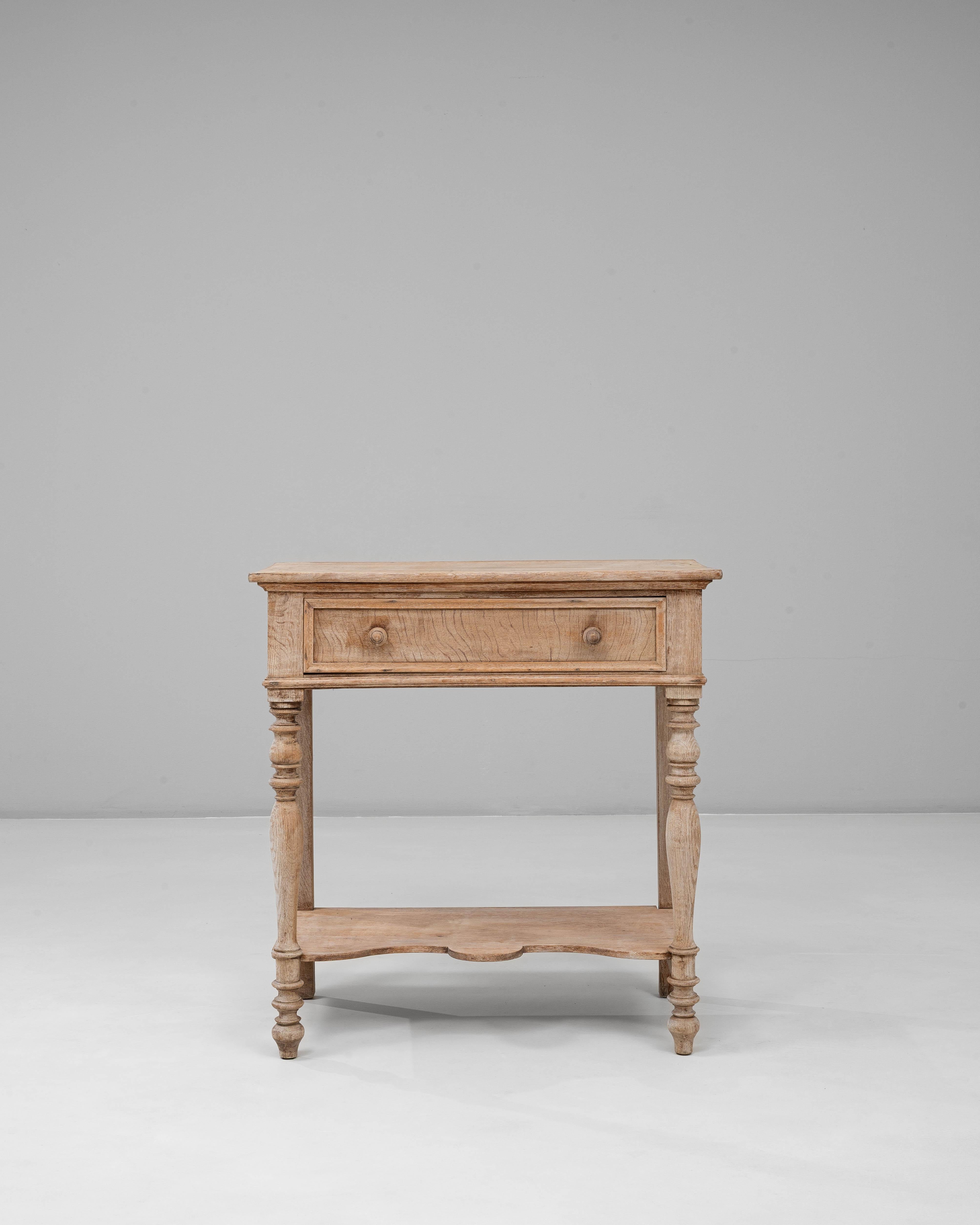 This 20th Century French oak console table with one drawer showcases the understated refinement and practical charm of traditional French craftsmanship. The bleached oak surface reveals a soft, natural patina that highlights the wood’s grain and