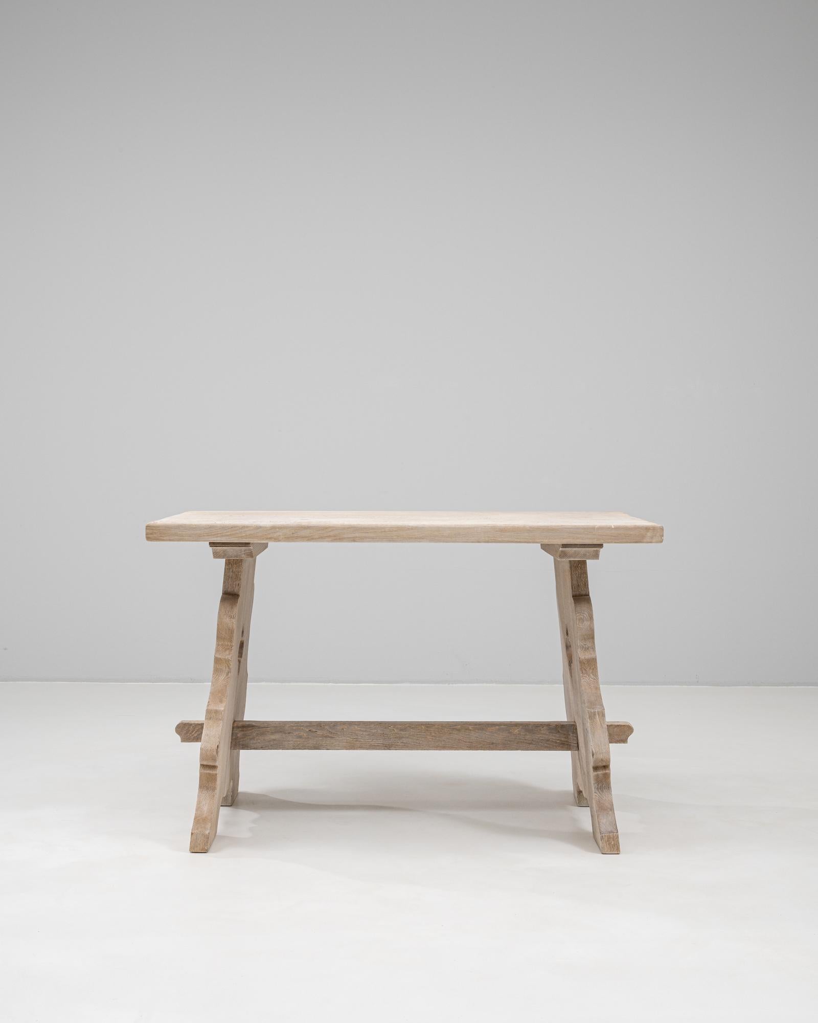 Fabriquée en chêne français massif, cette table de salle à manger du XXe siècle dégage un charme rustique avec sa patine vieillie et ses détails sculptés par des experts. La base de style tréteau présente des pieds aux formes élégantes avec des