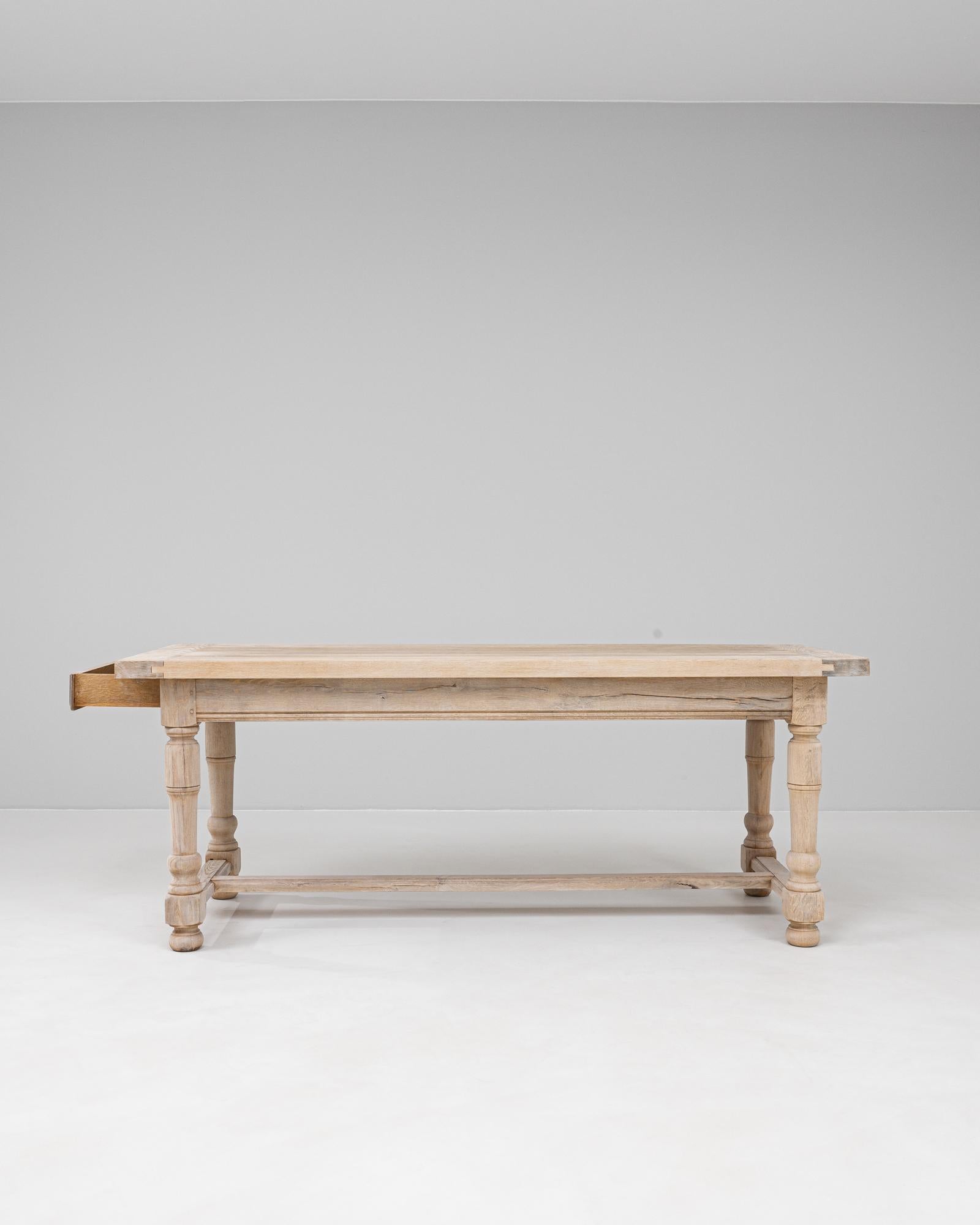 This 20th century French oak dining table exemplifies timeless provincial craftsmanship with its clean lines and balanced proportions. The solid oak construction features a rectangular plank top supported by turned legs and a box stretcher for added