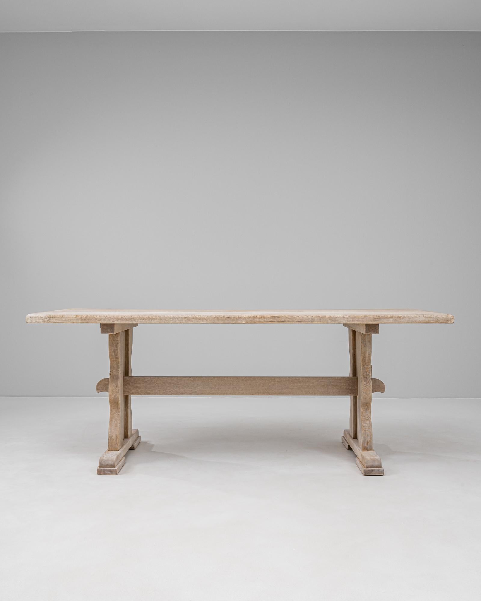 Table de salle à manger en chêne français du 20e siècle, avec une base sculpturale à tréteaux et des supports joliment façonnés reliés par un châssis central. La construction en chêne massif et la finition claire et naturelle mettent en valeur le