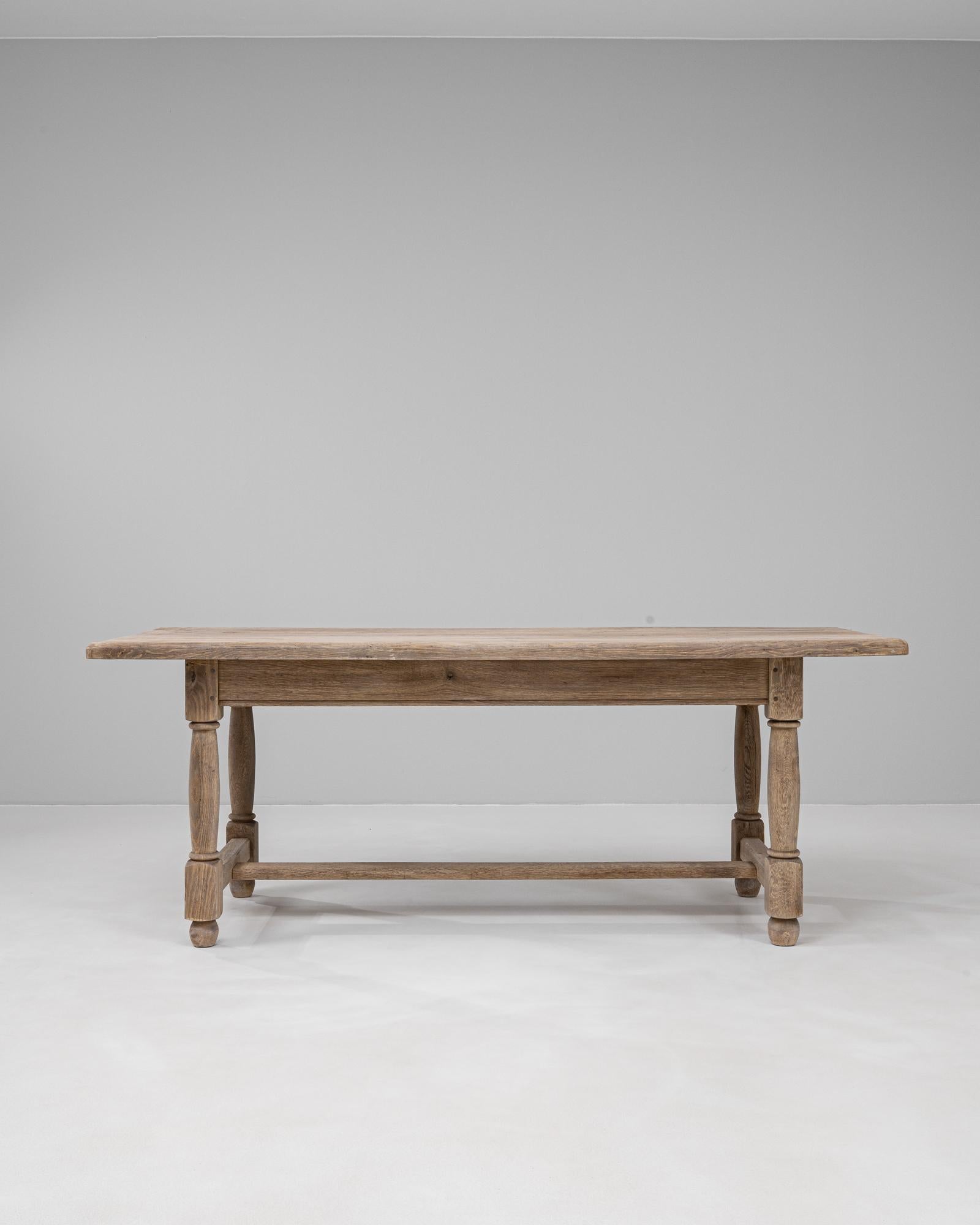 Table de salle à manger en chêne français du 20e siècle. Fabriquée en chêne massif, cette table incarne la chaleur et la durabilité caractéristiques du design provincial français. L'épais plateau rectangulaire repose sur des pieds tournés reliés par