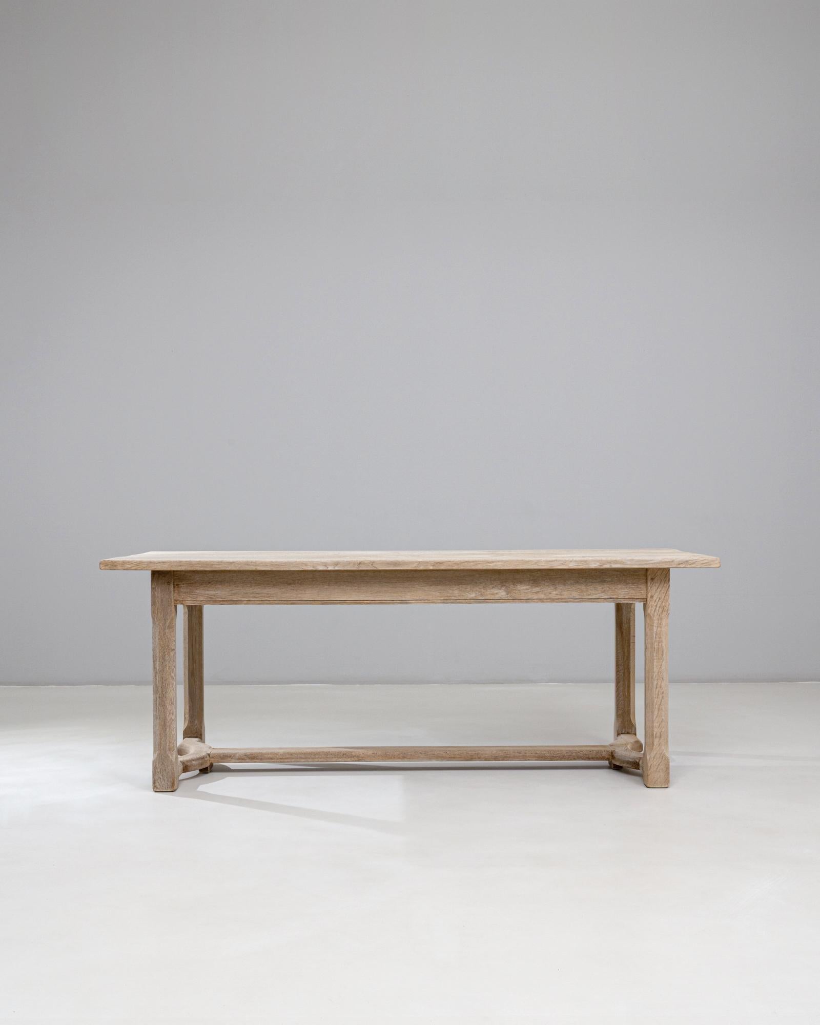 Esta mesa de comedor de roble francés del siglo XX presenta una silueta refinada pero discreta, que exhibe la tranquila elegancia característica de la artesanía provinciana. La larga tapa rectangular está hecha de roble macizo con una suave pátina