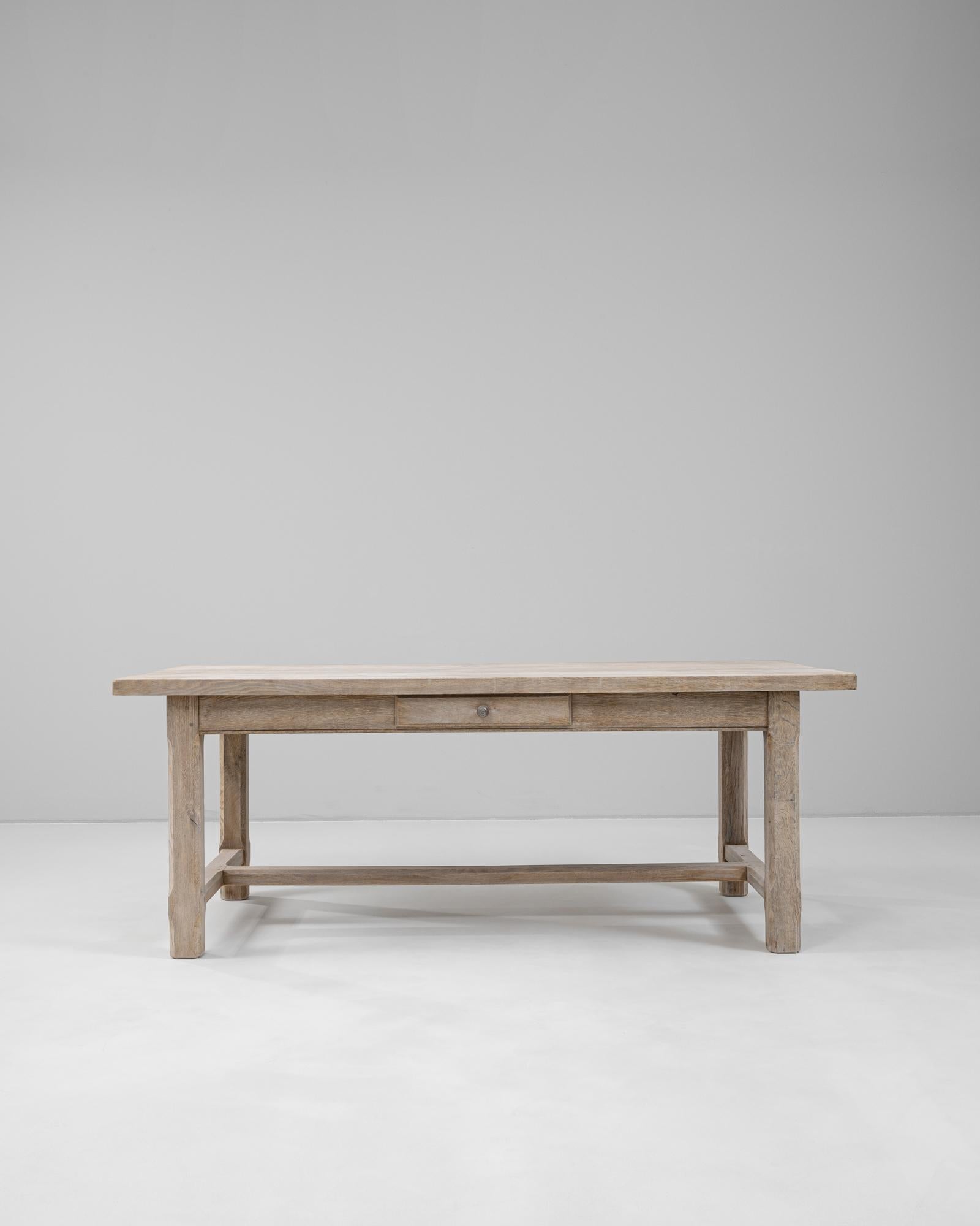 Fabriquée en France au cours du XXe siècle, cette table de salle à manger en chêne illustre la simplicité rustique et le design fonctionnel. La construction en chêne massif présente une finition blanchie naturelle qui met en valeur le grain et la