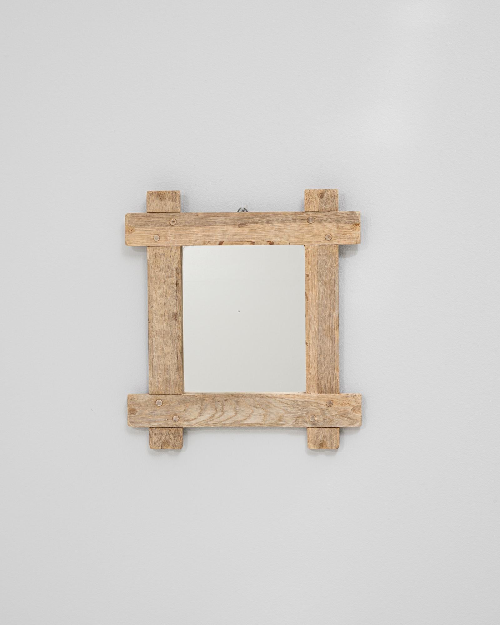 This 20th century French oak mirror features a rustic handcrafted frame with visible joinery and pegged construction, highlighting the integrity and charm of traditional woodworking. The solid oak has developed a soft, natural patina that enhances