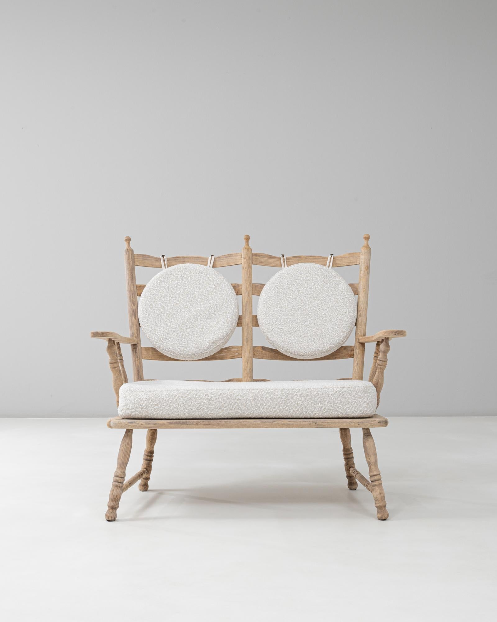 This 20th Century French Oak Spindle-Back Loveseat with Bouclé Cushions showcases a blend of traditional craftsmanship and modern refinement. Crafted from solid oak with a softly bleached finish, the frame features finely turned spindles along the