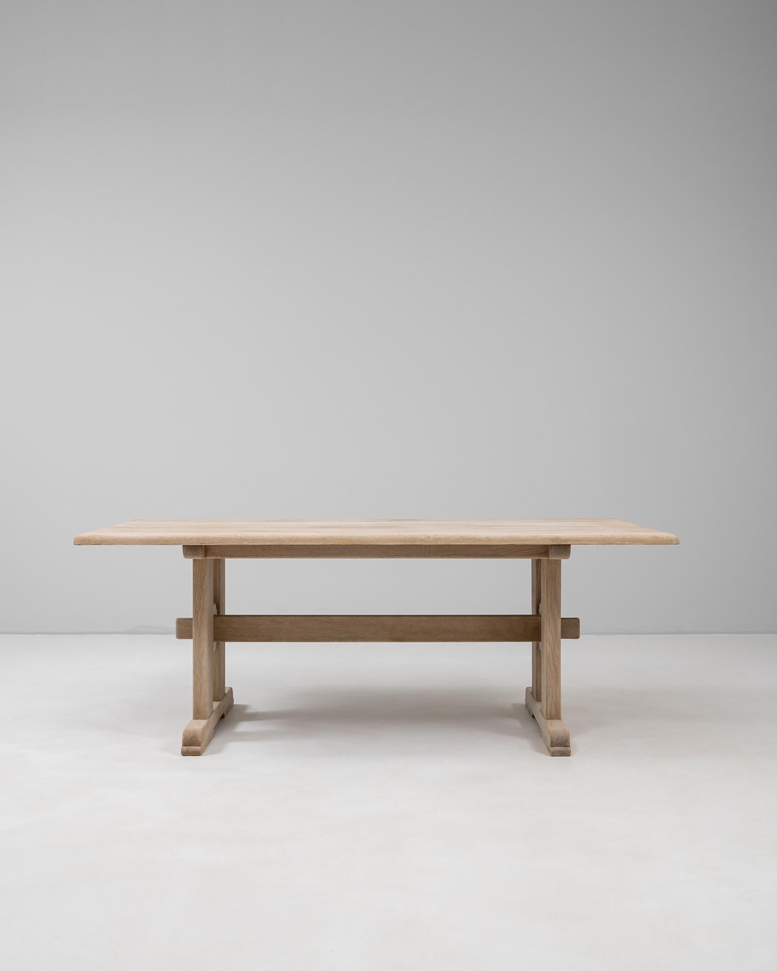 Cette table à manger à tréteaux en chêne français du XXe siècle est un exemple de savoir-faire intemporel et de raffinement rustique. Construite en chêne massif, la table présente un épais plateau rectangulaire aux bords doucement arrondis qui