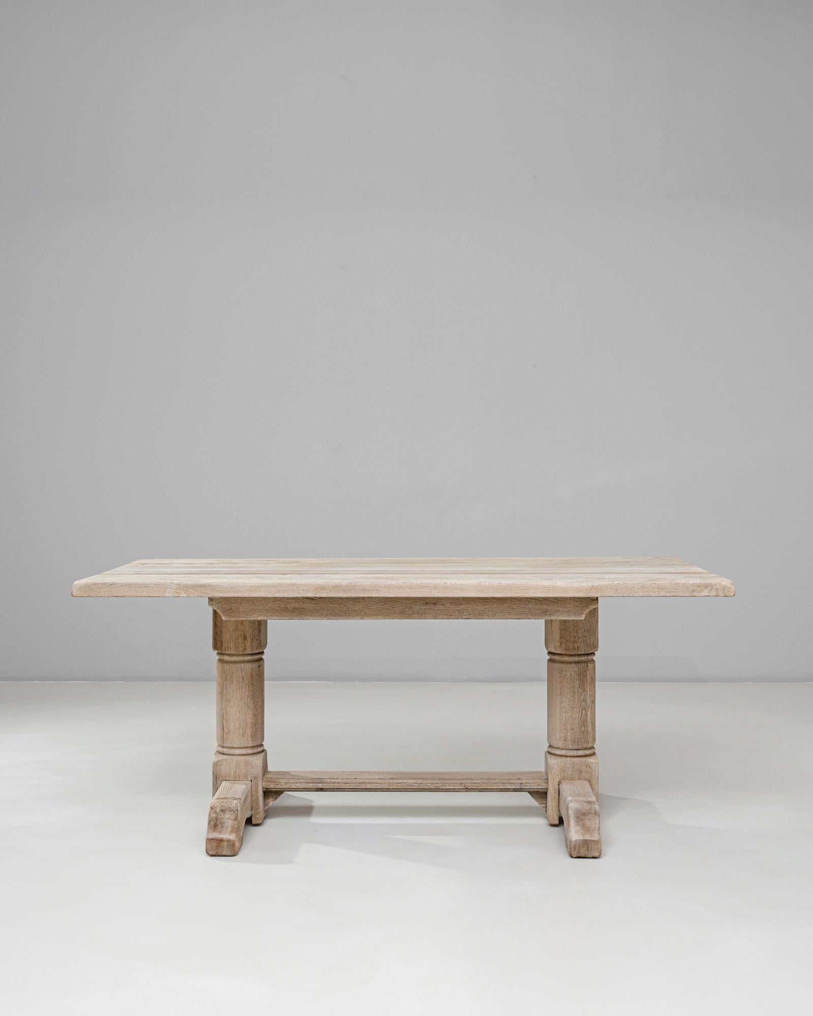 Cette table de salle à manger à tréteaux en chêne français du 20e siècle présente une silhouette architecturale audacieuse, ancrée dans l'artisanat traditionnel. L'épais plateau rectangulaire met en valeur le grain naturel et la texture doucement