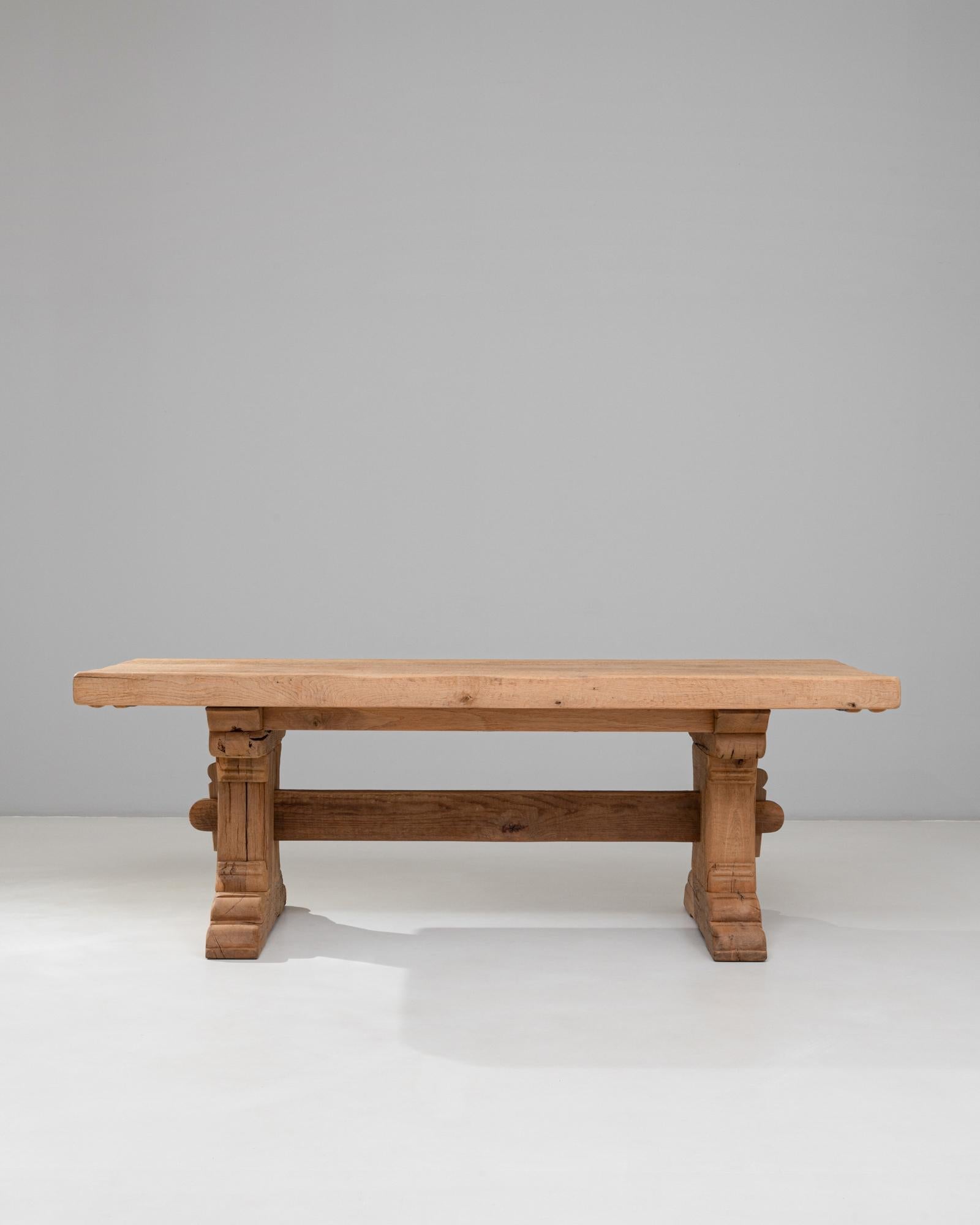 Cette table de salle à manger à tréteaux en chêne français du 20e siècle illustre l'attrait durable de l'artisanat traditionnel, rendu dans un chêne massif substantiel et magnifiquement vieilli. Le plateau rectangulaire épais présente des
