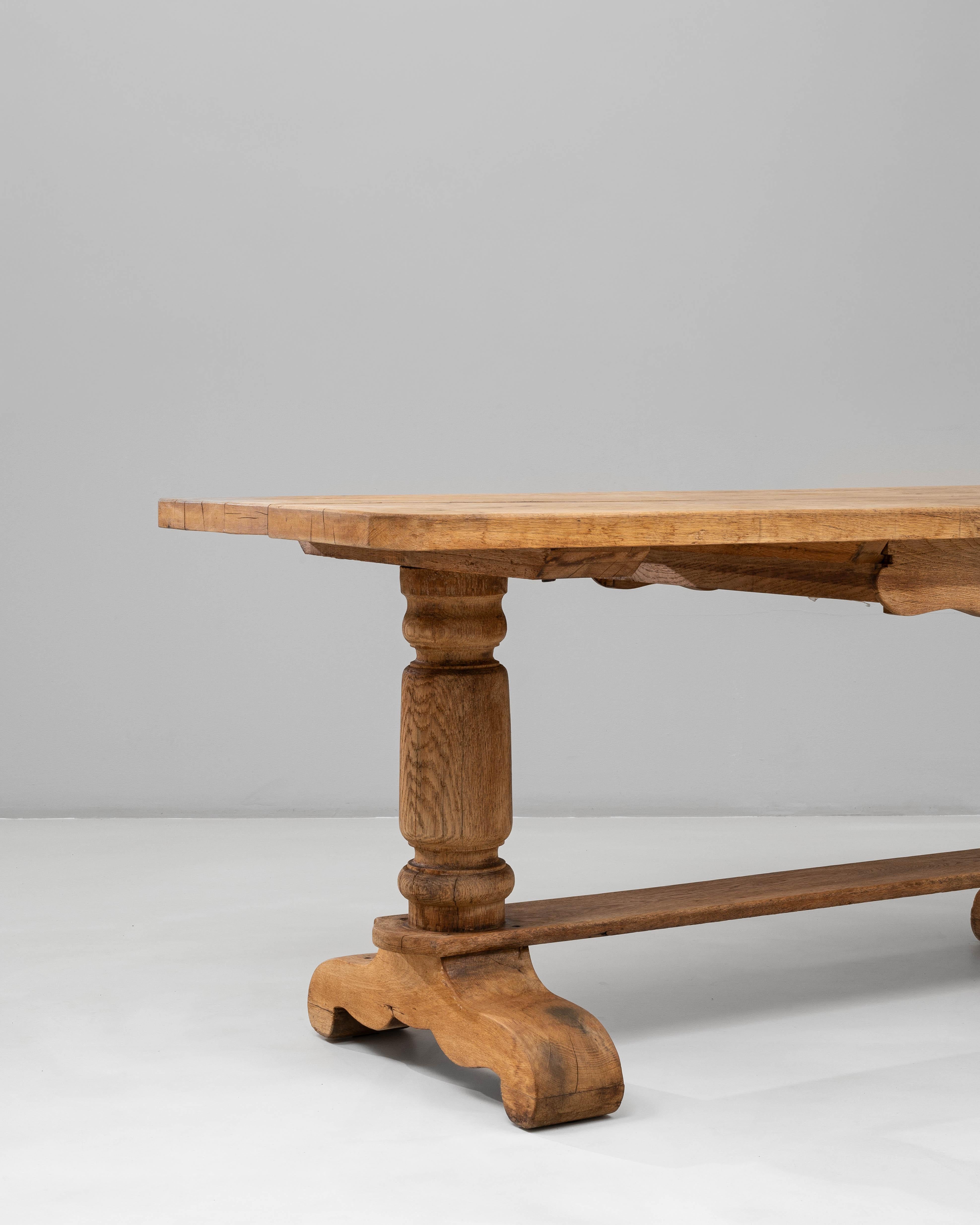 Cette table de salle à manger à tréteaux en chêne français du 20e siècle présente une finition chaude et naturelle qui met en valeur le grain, la texture et l'authenticité de sa construction en bois massif. Le plateau rectangulaire repose sur deux