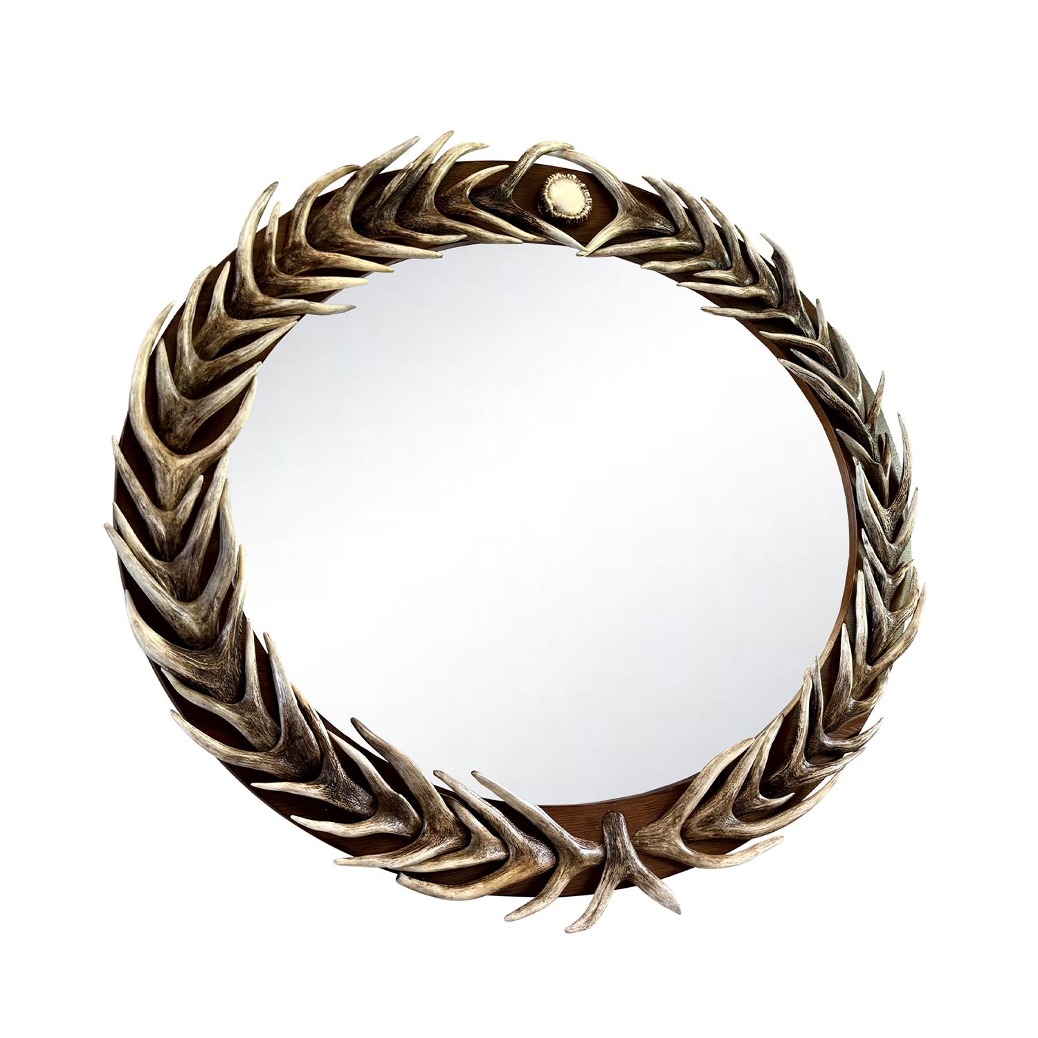 Un extraordinario espejo vintage enmarcado por un atrevido y escultural motivo de astas talladas, dispuestas al estilo de una corona de laurel. Esta espectacular pieza de pared está elaborada con astas de imitación meticulosamente representadas, que