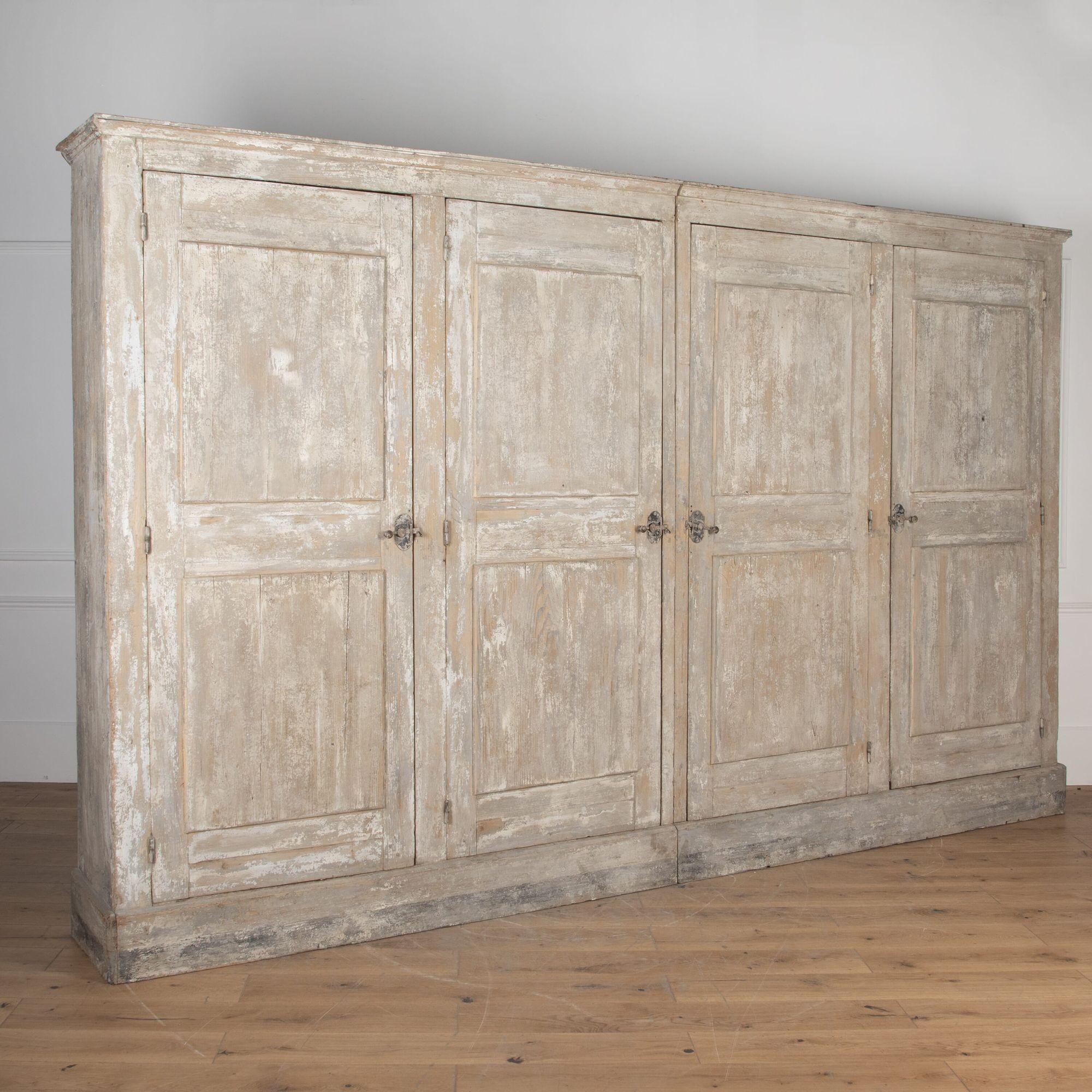 Monumental 20th century painted four door cupboard. 
This armoire has wonderful elegant proportions. It offers four large panelled doors with spacious shelves to the interior. 
This piece is painted grey and retains all of its original decorative