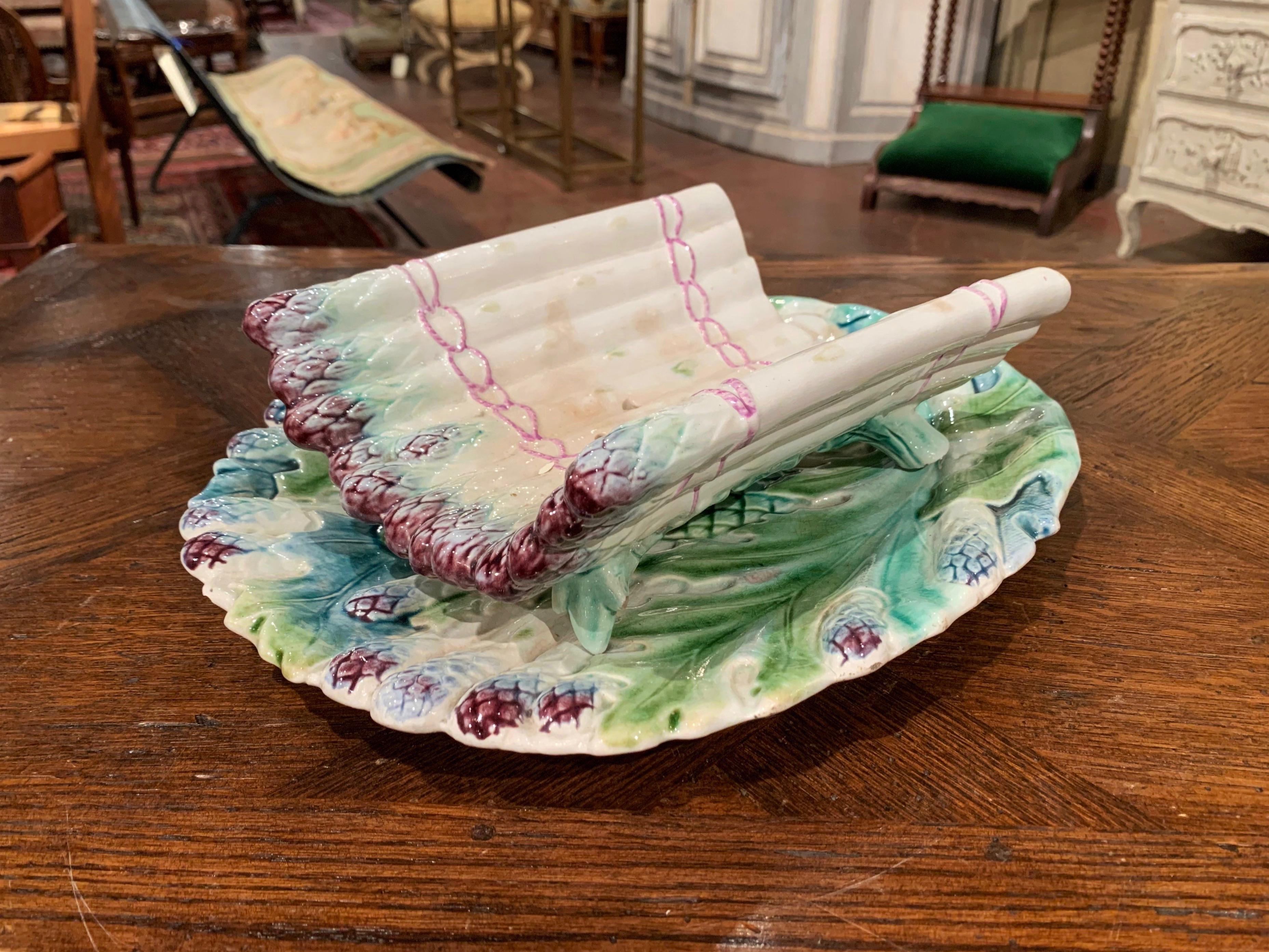 Dress up your dining room table or kitchen counter with this fine colorful hand painted Majolica asparagus dish. Sculpted in France, circa 1920, the two-piece set has a bottom platter with high relief asparagus and artichoke motifs, and a rounded