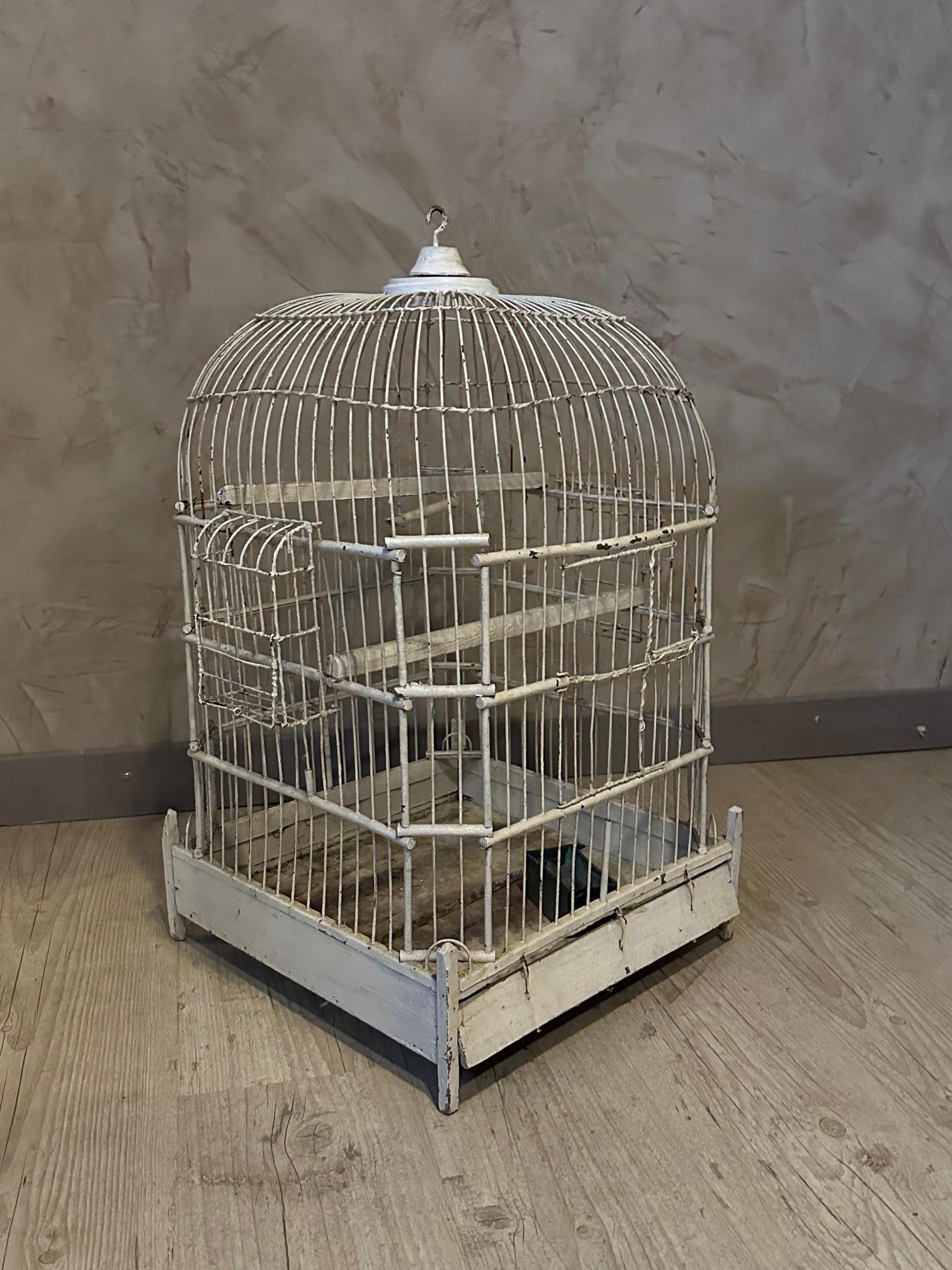 Schöner Vogelkäfig aus den 1920er Jahren aus weiß lackiertem Metall und Holz.
Schwenktür. Futterstelle und Sitzstange.