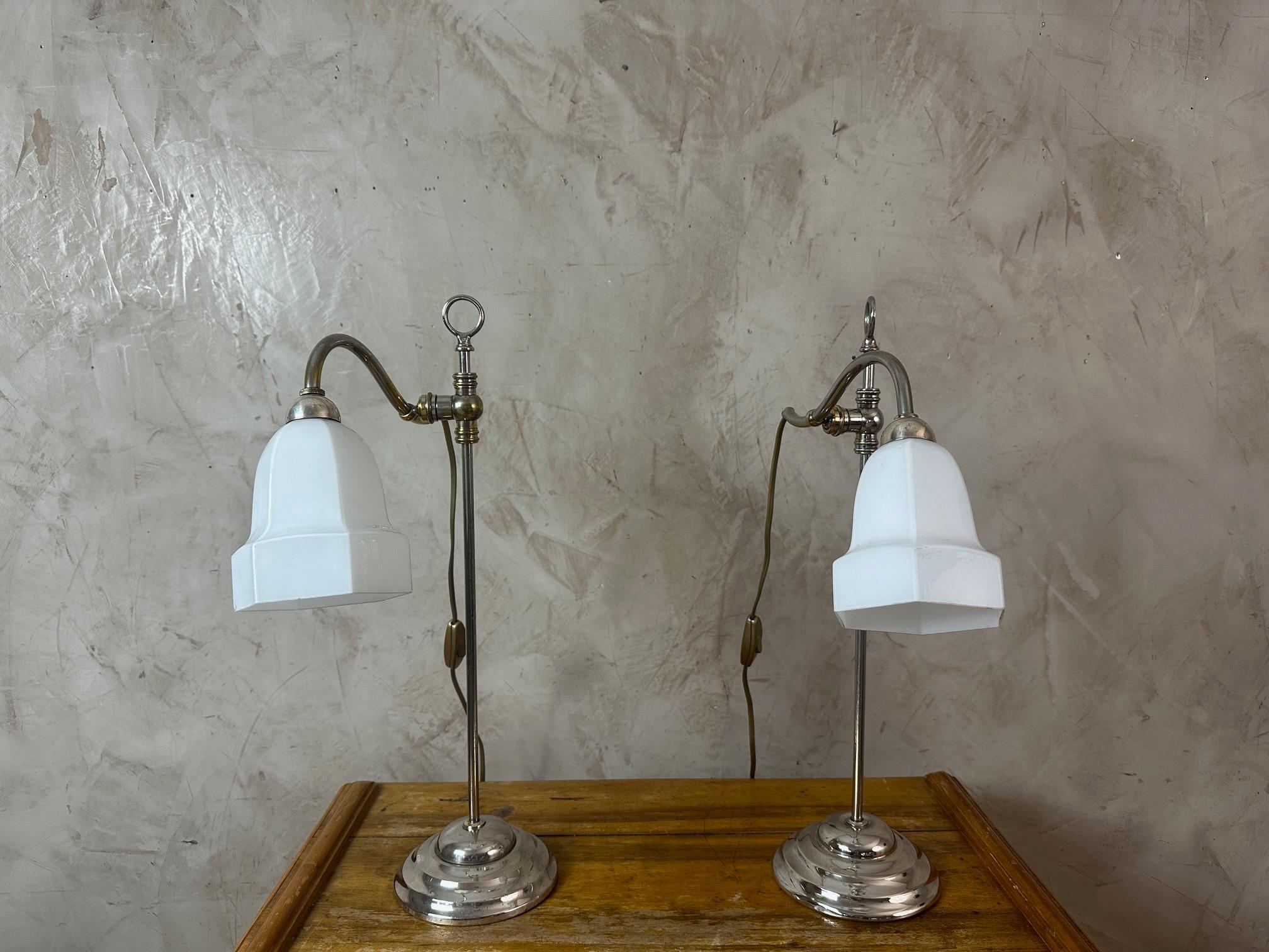 Elegant pair of desk lamps dating from the 1930s, featuring a refined and timeless design.
Each lamp is composed of a chrome-plated metal base and a white opaline glass shade, with a simple yet luminous charm. The angled arm allows for adjustable