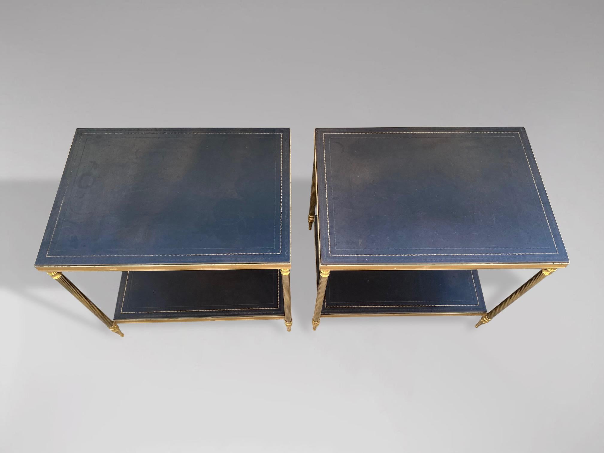 An elegant pair of versatile and substantial two tier leather top and brass side tables. A pair of French neoclassical side or end tables, featuring two gilt tooled black leather rectangular tiers, supported within an elegant brass framework with