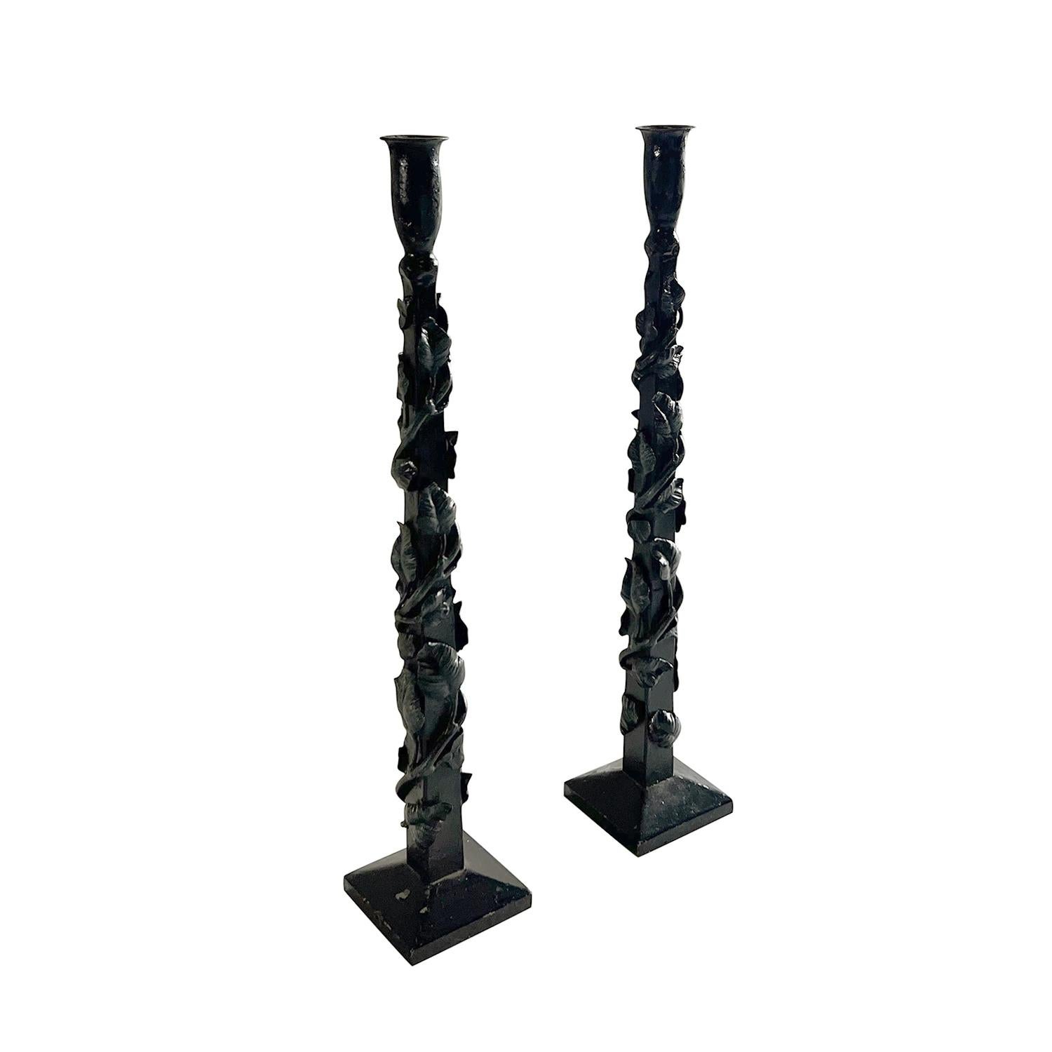 A vintage French pair of handsome brutalist iron candleholders hand forged and hammered with their original painted finish. These elegant and simple pair of candle sticks have perfect proportions, great details and sit on square feet. Hand forged in