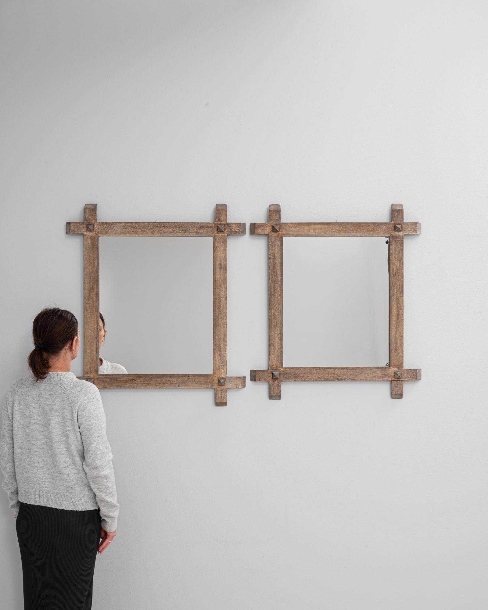 Questa coppia di specchi in legno di quercia del XX secolo presenta un design unico e scultoreo ispirato alle tecniche di falegnameria tradizionali. Le cornici quadrate sono costruite con tenoni angolari a vista, ognuno dei quali è accentuato da un
