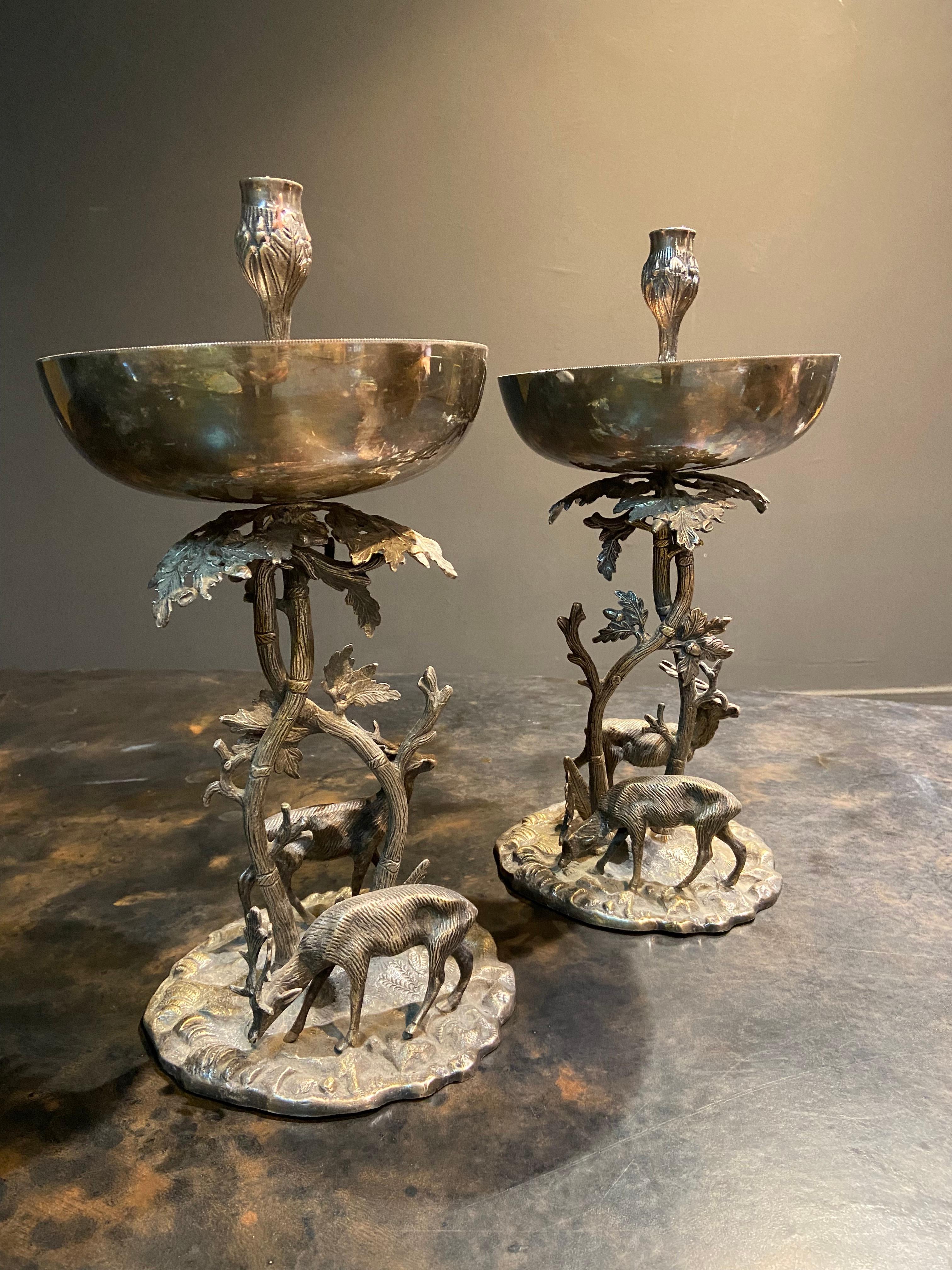 French pair of silver plated bronze candlesticks with brocade decoration on a mound, the branch supporting a cup and the candlestick surrounded by couple of deers.
France, circa 1950.