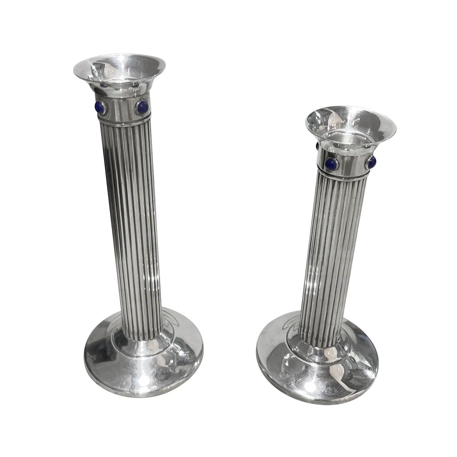 A vintage pair of candlesticks made of hand crafted silver-plated metal, sold by Cartier in good condition. The fluted pair of candle holders are enhanced by four detailed round lapis lazuli stones, supported by a round broad base and a ribbon. The