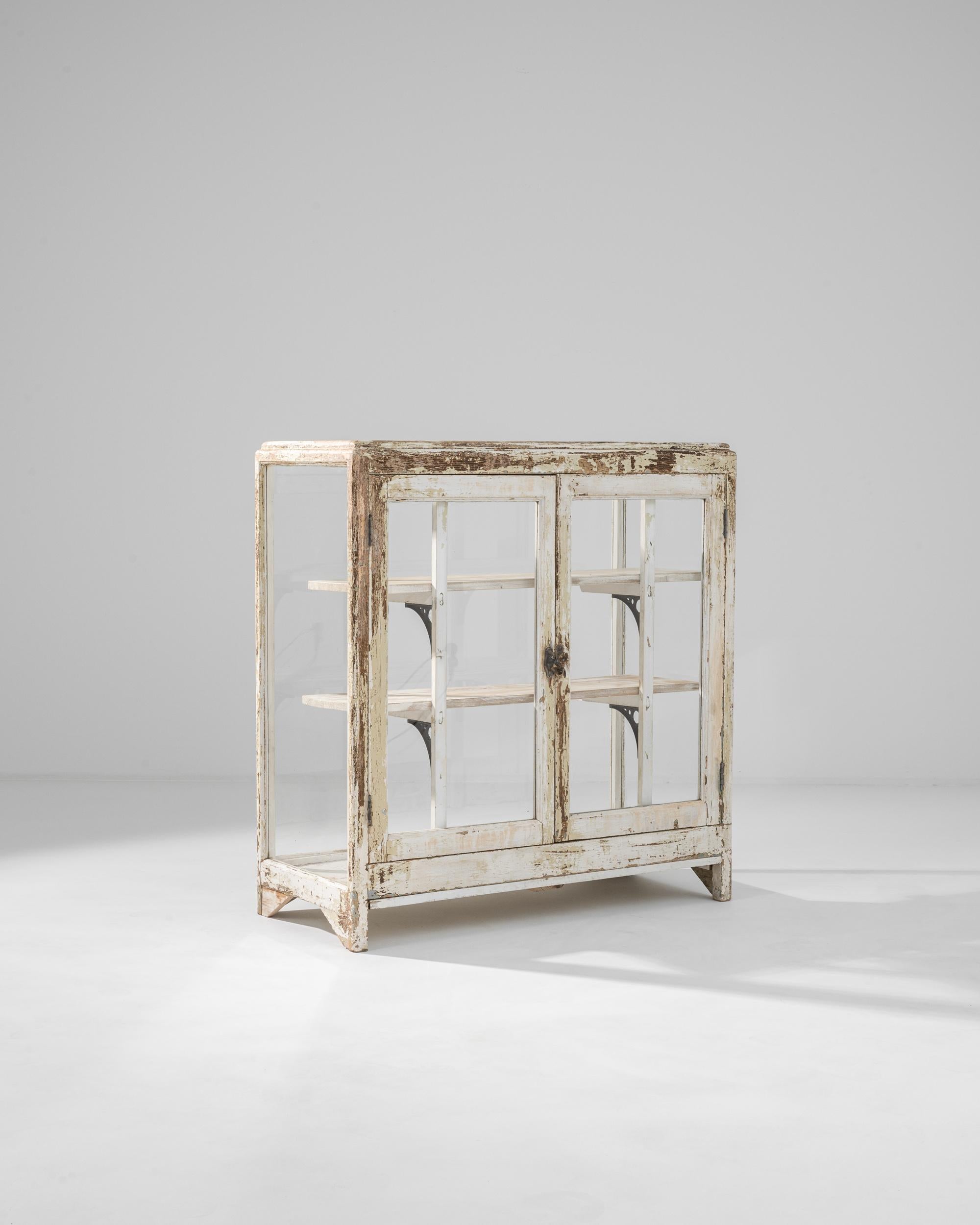 A distinctive patina gives this vintage vitrine a romantic air of nostalgia. Made in France in the 20th century, glass windows on all four sides of the case maximize natural light, illuminating the objects placed on the wooden shelves within. The