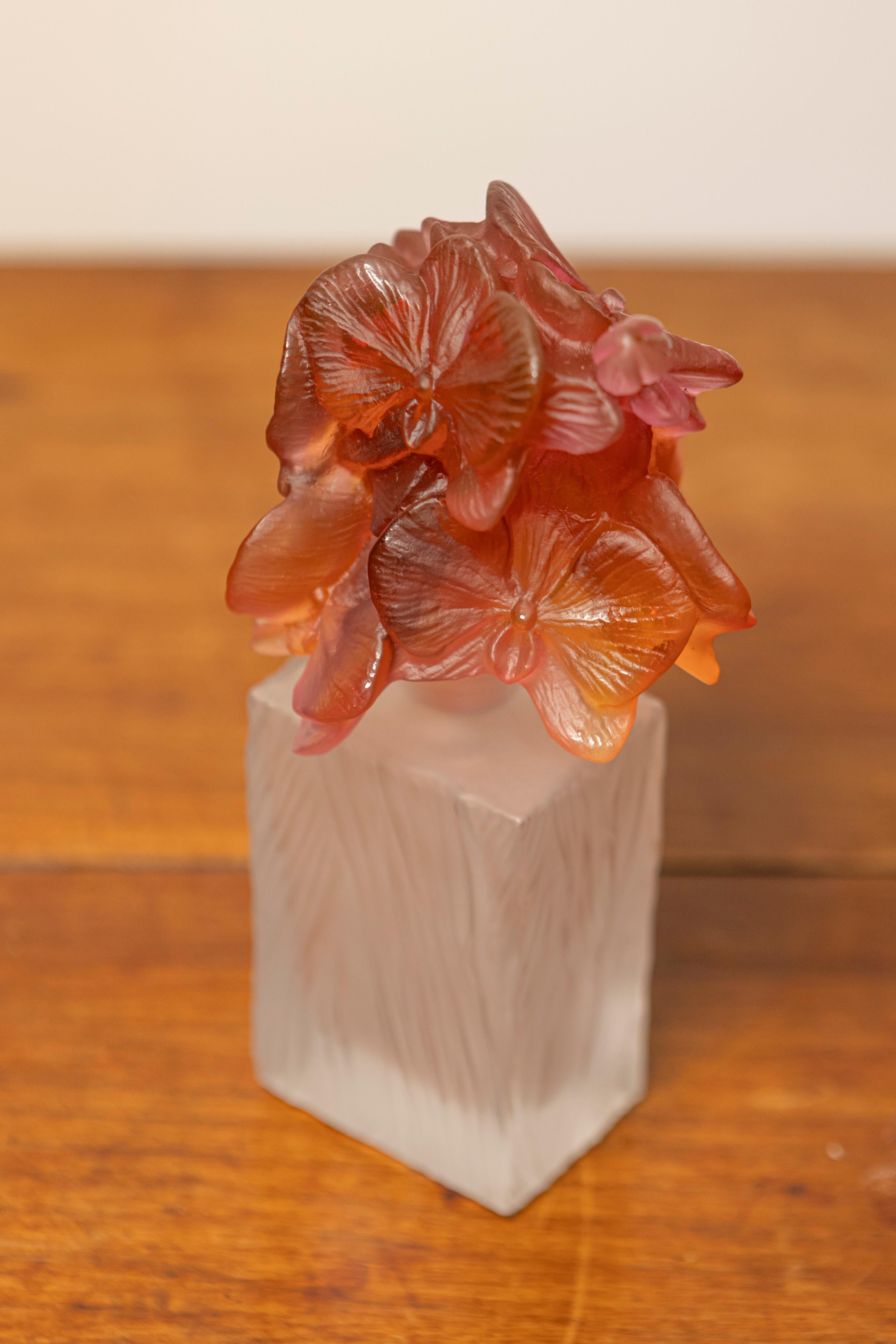 This 20th-century French perfume bottle is a striking example of Daum glass craftsmanship. The bottle features a frosted glass body with delicate, swirling patterns, and is topped with beautifully sculpted floral glass details in shades of amber and