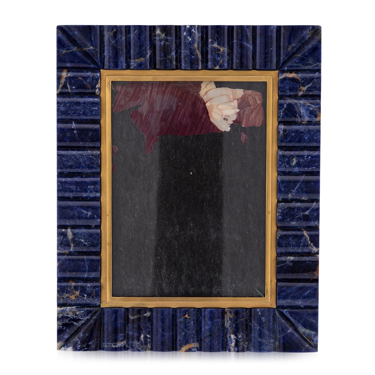 A very attractive photograph frame made by Christian Dior, made in France around the turn of the century. The yellow metal frame surrounded by a polished, fluted sodalite border mimicking lapis lazuli. An elegant and modern take on the traditional