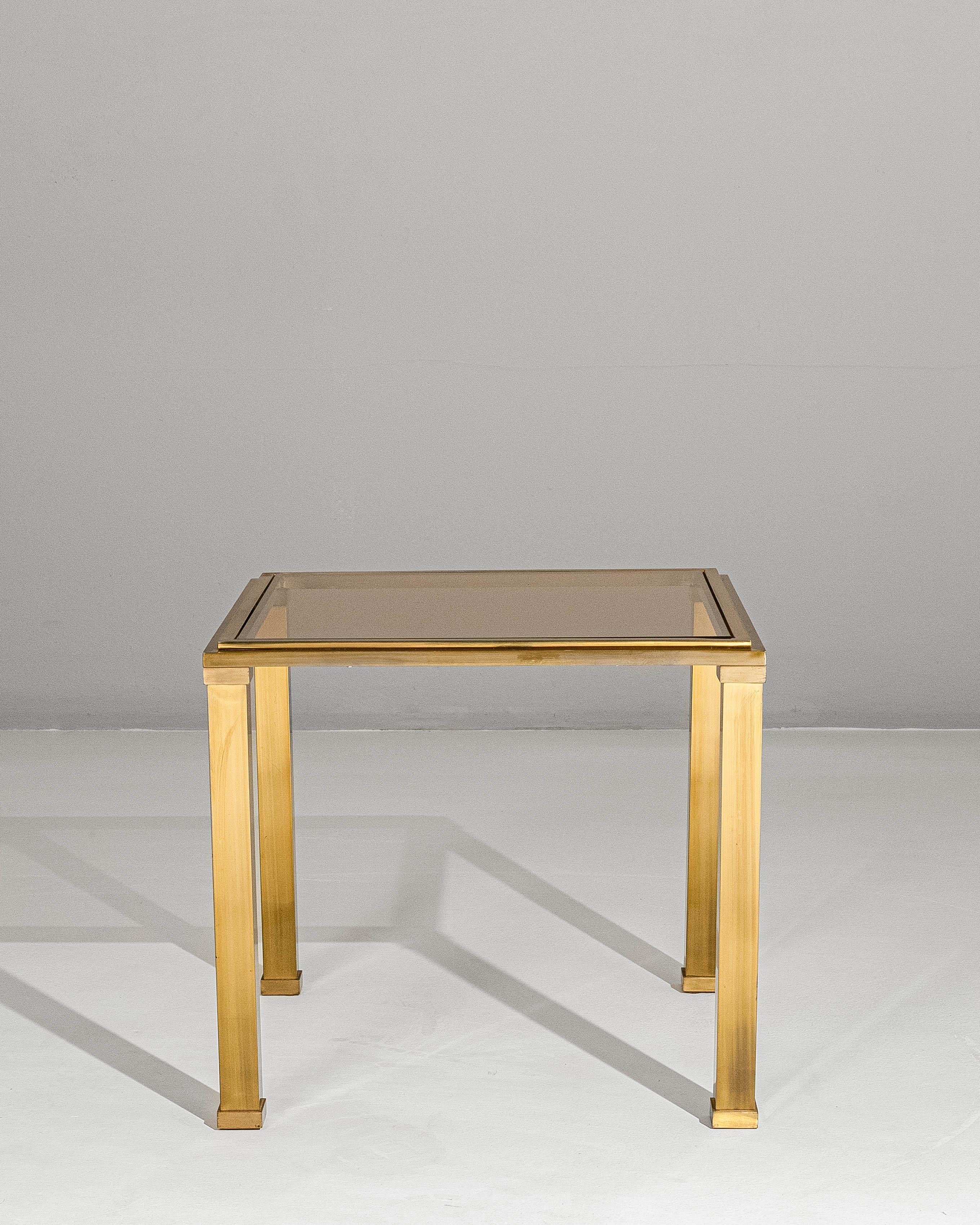 This 20th century French coffee table in the style of Pierre Vandel exemplifies the refined glamour and clean-lined sophistication associated with late modern French design. Constructed with a polished brass frame, the table features crisp