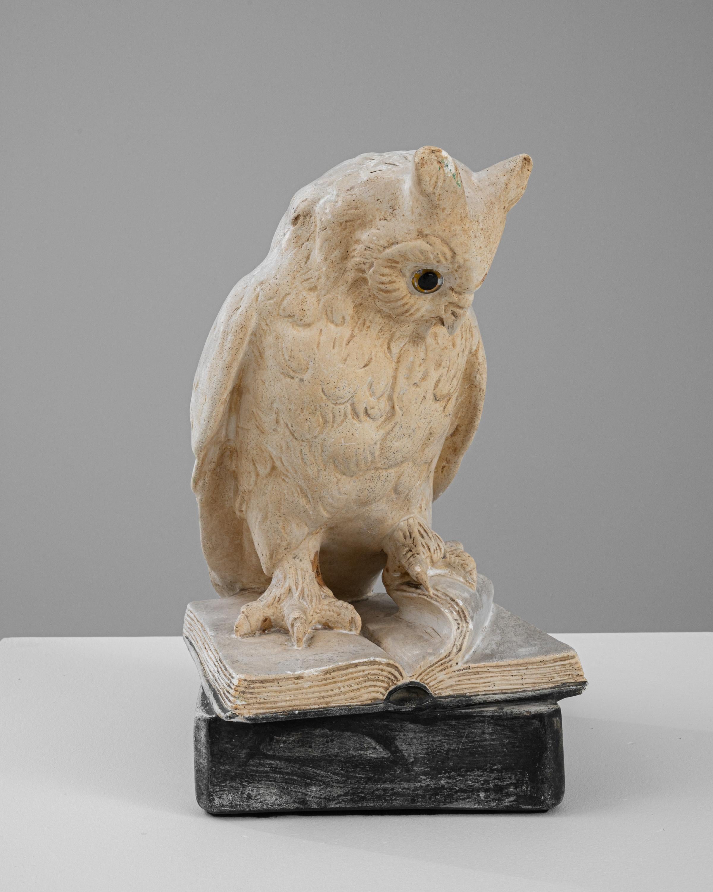 This 20th Century French Plaster Sculpture offers a unique and artistic depiction of an owl perched thoughtfully on an open book. The sculpture combines intricate detailing with a subtle palette of natural plaster tones to highlight the textures and