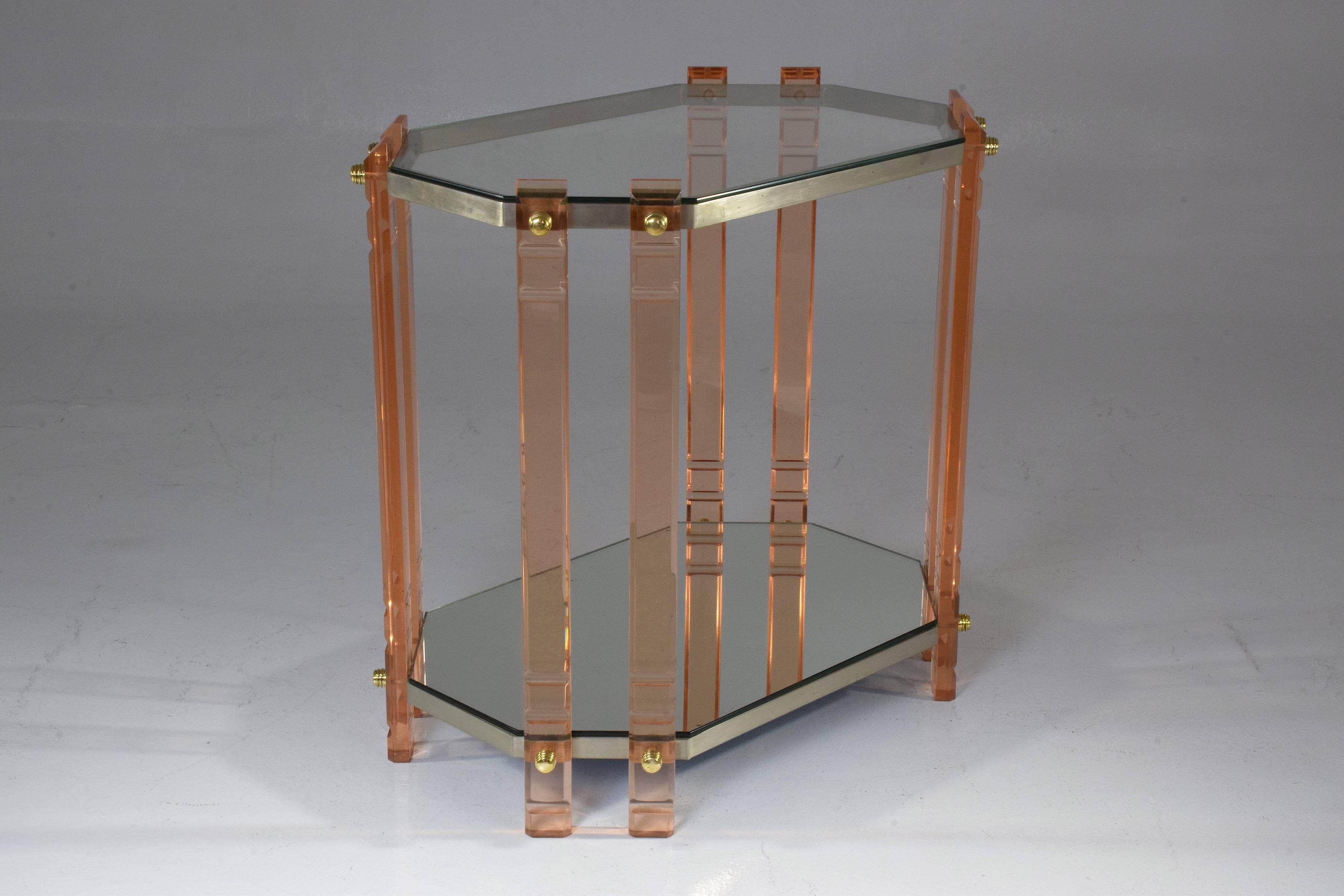 A 20 century French vintage storage piece, accent table, étagère or bar cart composed of a light pink plexiglass structure with polished brass screws, stainless steel shelves with mirrored glass table tops. This piece will highlight any living area