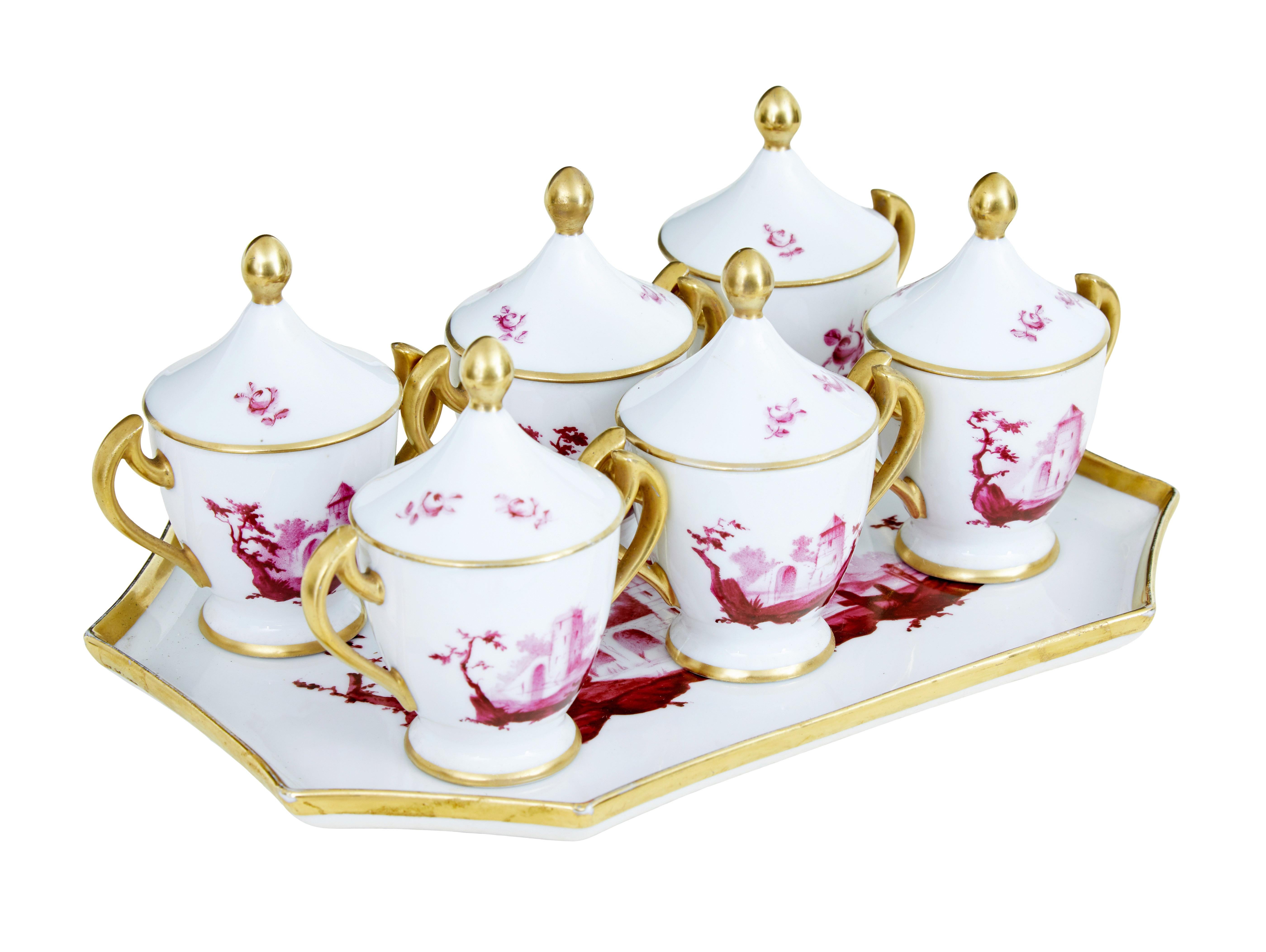 20th century French porcelain 7 piece dessert set, circa 1920.

Here we have what we believe to be a french porcelain dessert set. Decorated with gilt handles and lids, set consists of 6 small dessert cups with lids standing on matching plate.