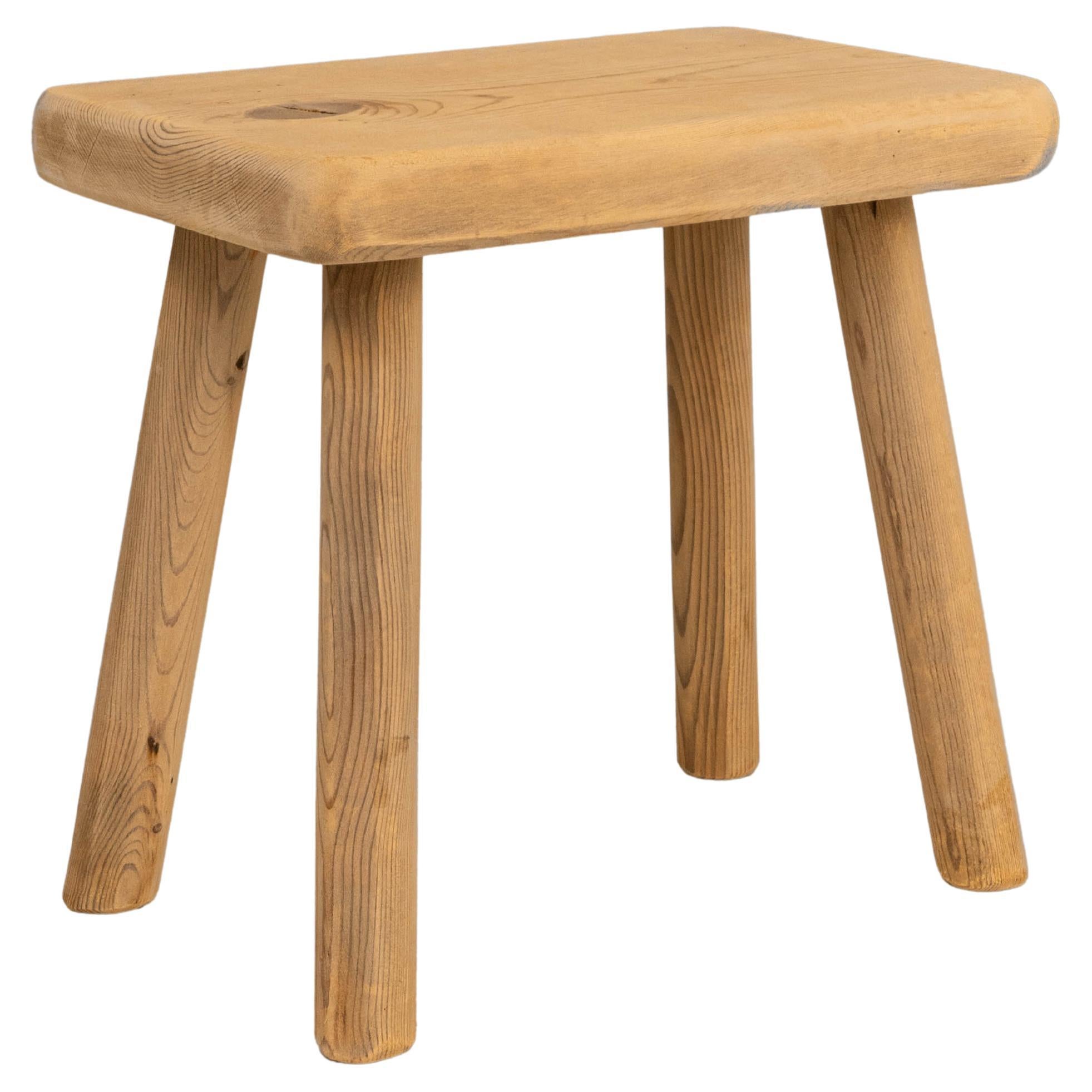 This 20th Century French primitive wooden stool embodies the simplicity and honesty of traditional rural craftsmanship. Built from solid wood with a warm, naturally aged surface, the stool features a rectangular seat with softly rounded edges and