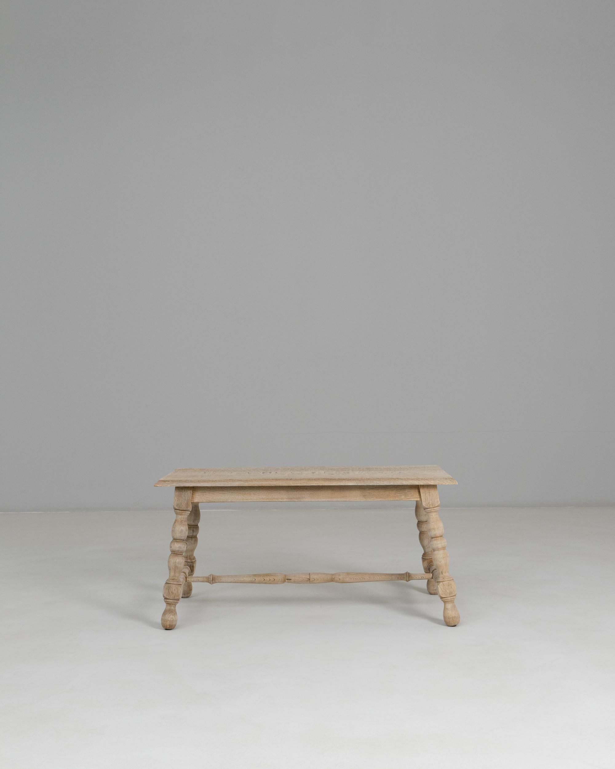 This 20th Century French Provincial oak coffee table showcases the charm and character of traditional countryside craftsmanship, featuring a warm, natural patina and beautifully aged surface. The rectangular top sits over four turned legs, each