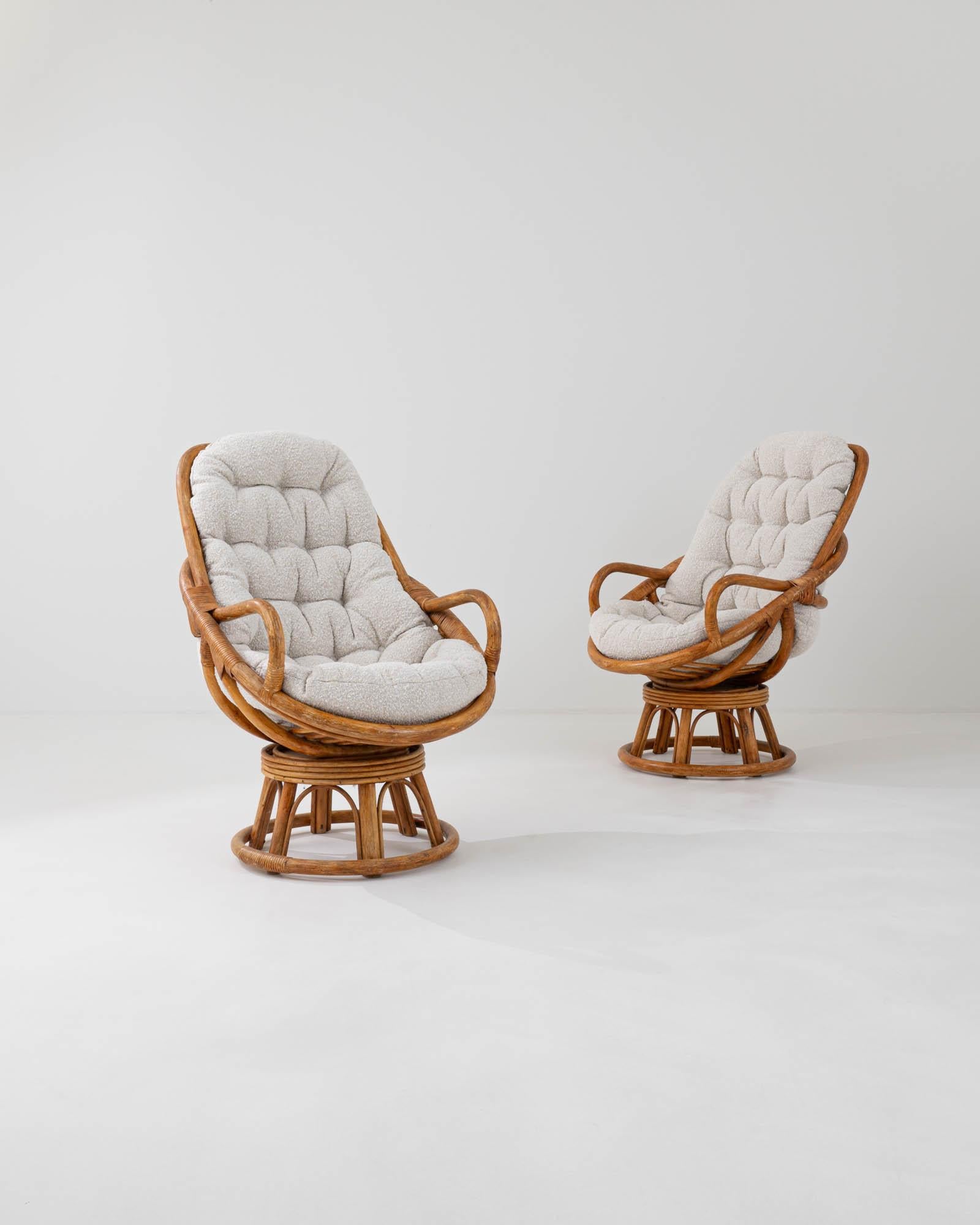 This pair of cozy swivel armchairs, originating from 20th-century France, seamlessly integrates a swiveling mechanism into the rattan base for smooth rotation. The upper portion features an appealing design with smoothly rounded armrests and tufted