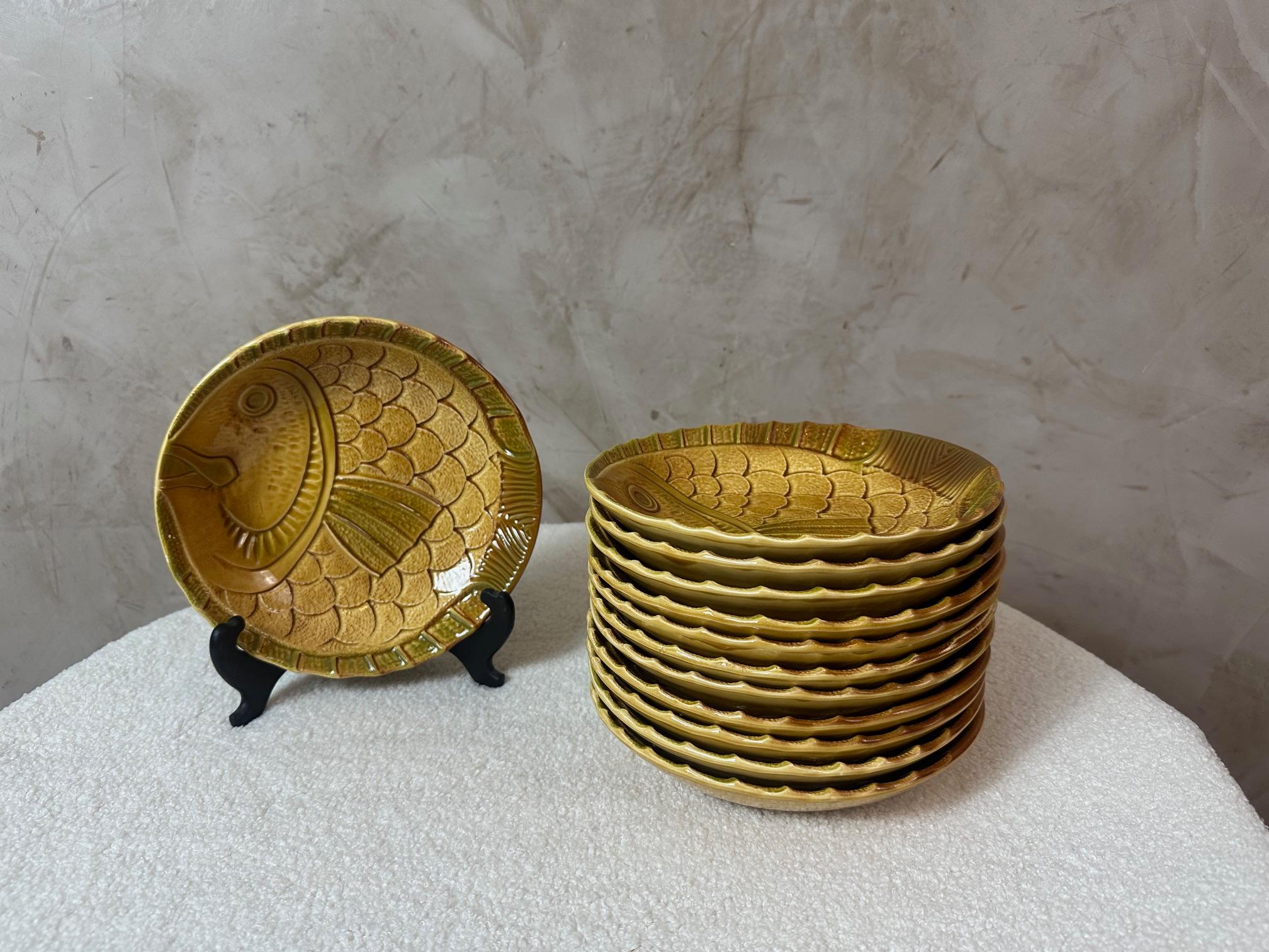 Superbe ensemble de 12 assiettes creuses en céramique émaillée (majolique) décorées d'un motif de poisson en relief, fabriquées par les ateliers d'art de Revernay en France.

Ces assiettes, d'un charmant ton brun miel, présentent un motif détaillé