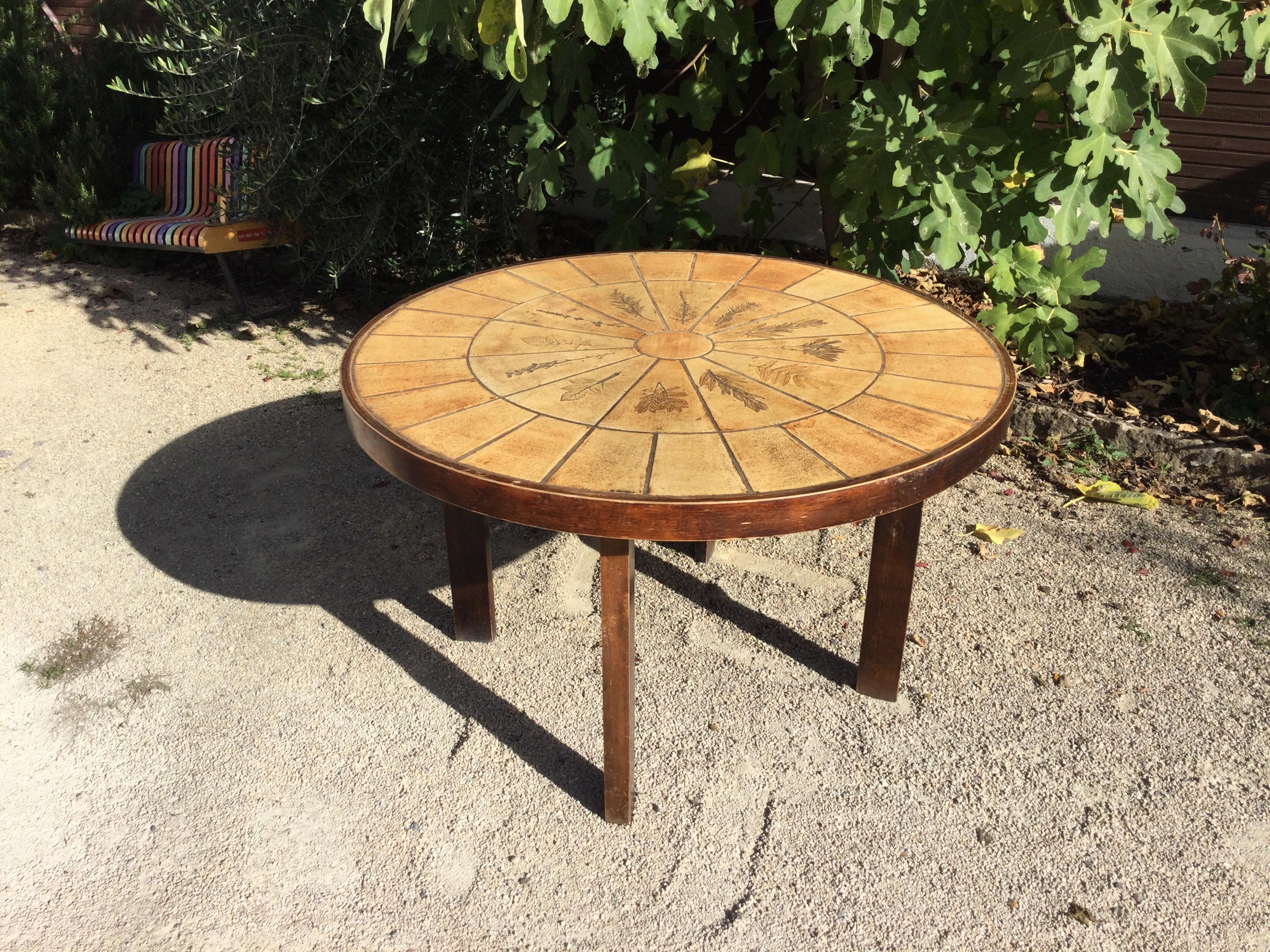 Rare dining table made by Roger Capron, famous French designer in the 1960s. 
The top of the table is made with ceramics and we can see different herbs. The base is made with wood. Show some consistent with age and use. 
There are some model like